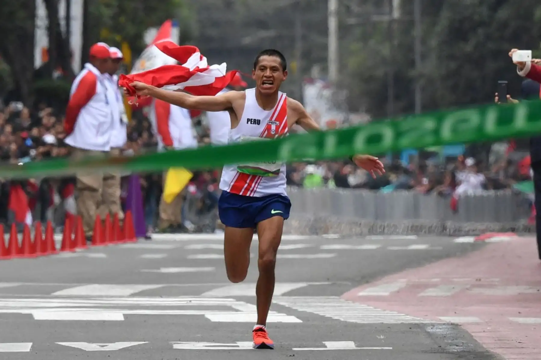 Christian Pacheco saluda al público mientras se acerca a la línea de meta. El atleta peruano ganó la medalla de oro en el maratón masculino de los Juegos Panamericanos Lima 2019, el 27 de julio de 2019. Foto: AFP