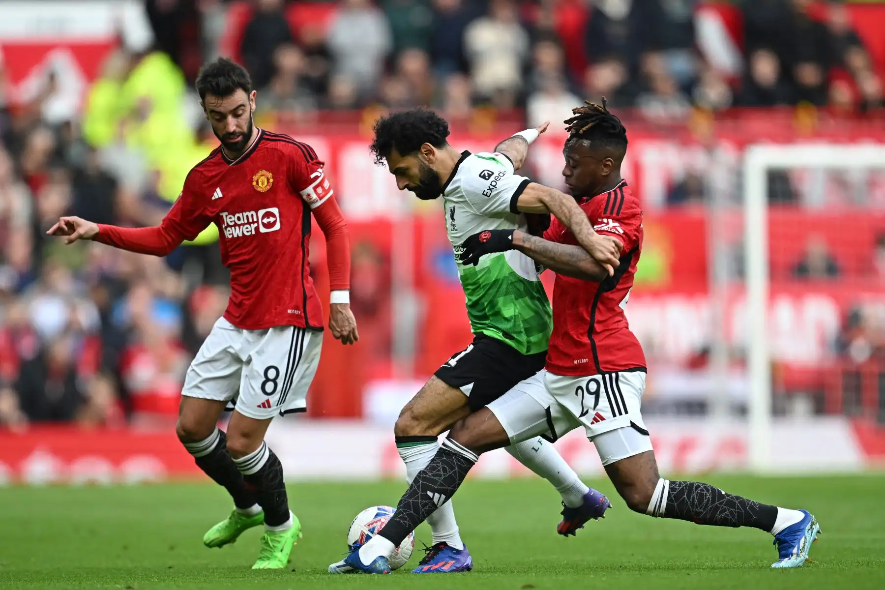 El delantero egipcio del Liverpool Mohamed Salah compite con el centrocampista portugués del Manchester United Bruno Fernandes y el defensor inglés del Manchester United Aaron Wan-Bissaka  durante el partido de fútbol de los cuartos de final de la Copa FA inglesa entre el Manchester United y Liverpool. Foto: ANDINA/AFP