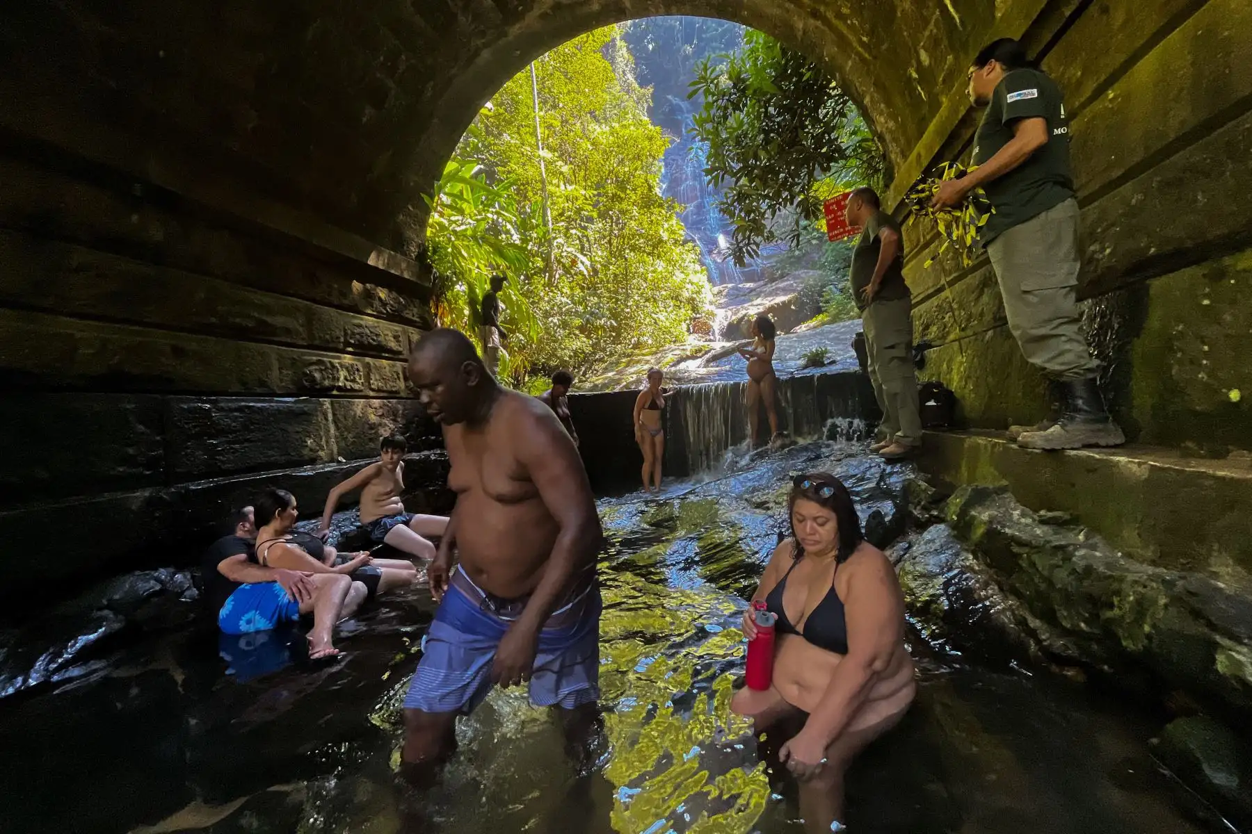 La gente se refresca en la cascada Taunay en el Parque Nacional Tijuca en Río de Janeiro, Brasil, el 17 de marzo de 2024. Una nueva ola de calor está azotando Brasil, con temperaturas récord que llevaron el domingo a los residentes de Río de Janeiro y Sao Paulo a verter hacia playas y parques. En el oeste de Río, la sensación térmica alcanzó los 60,1 grados centígrados el sábado. Foto: AFP