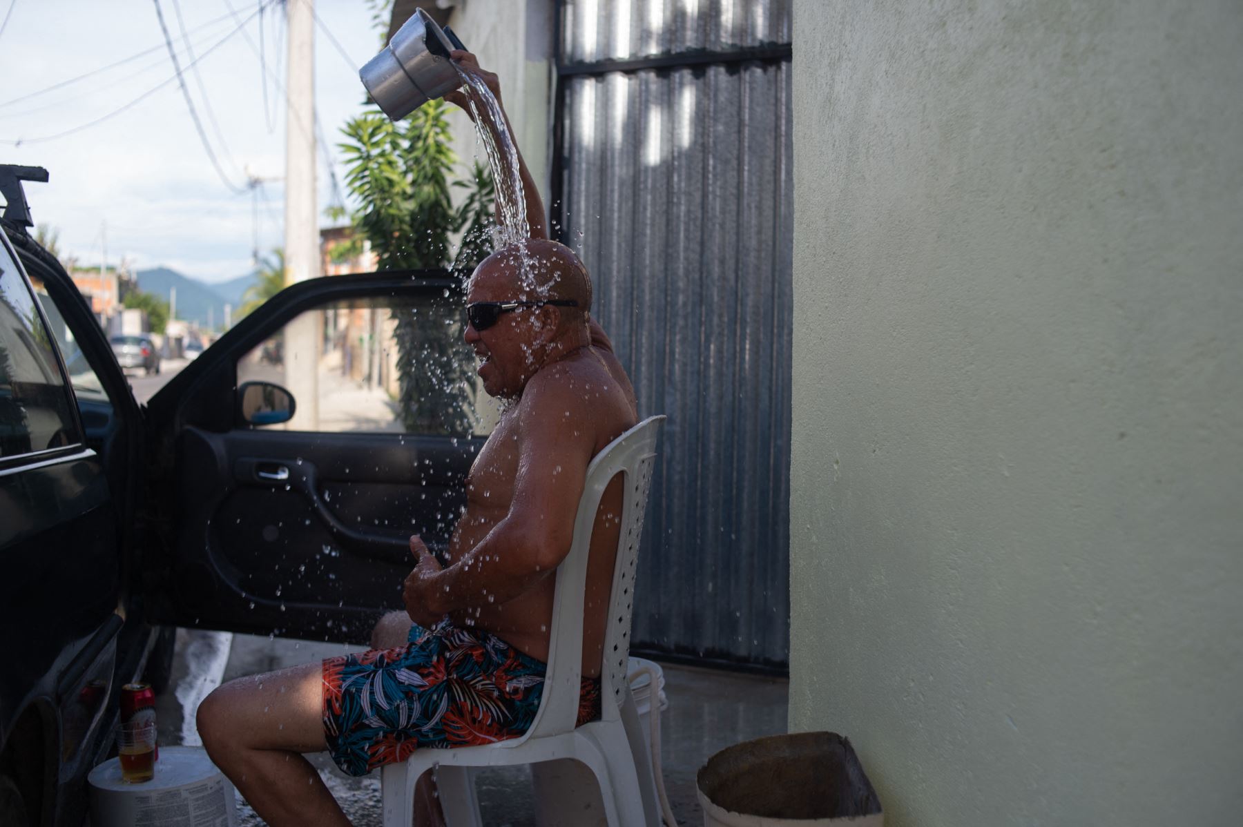 Un hombre arroja agua sobre su cabeza mientras está sentado en la calle durante una ola de calor, en el barrio de Guaratiba en Río de Janeiro, Brasil, el 17 de enero de 2024. Foto: AFP