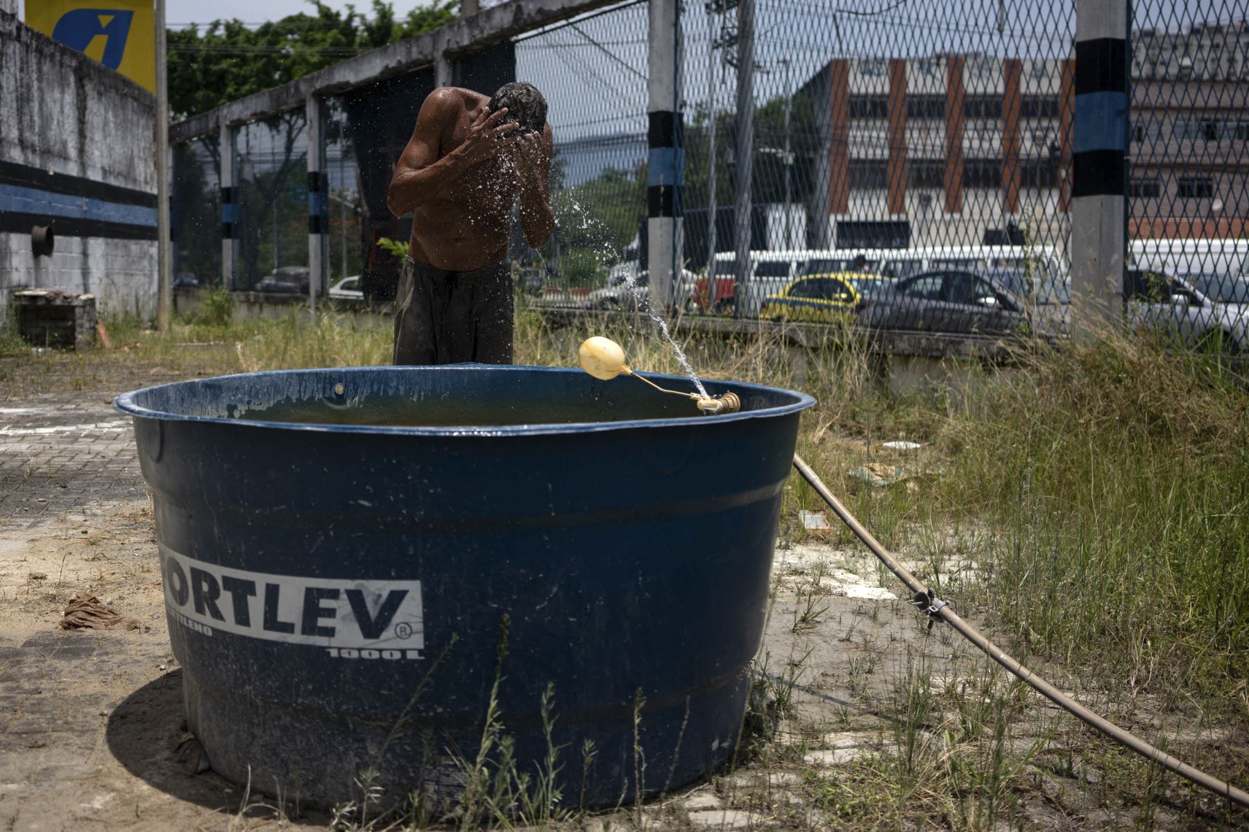 Un trabajador se refresca con una ducha improvisada en la zona norte de Río de Janeiro, Brasil. Foto: AFP