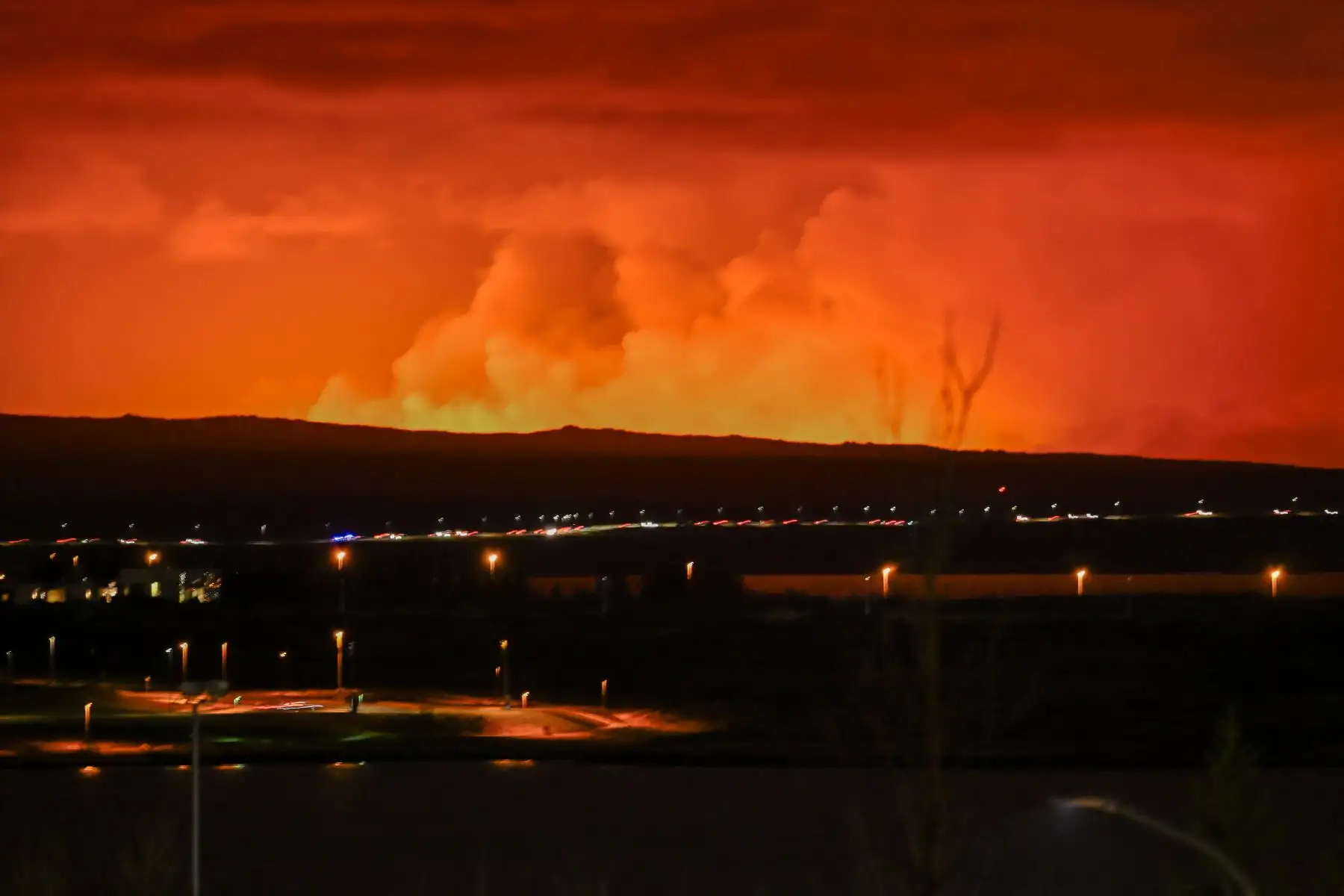 El cielo se tiñe de naranja mientras lava fundida fluye desde una fisura en la península de Reykjanes al norte de la ciudad evacuada de Grindavik, en el oeste de Islandia. Foto: AFP