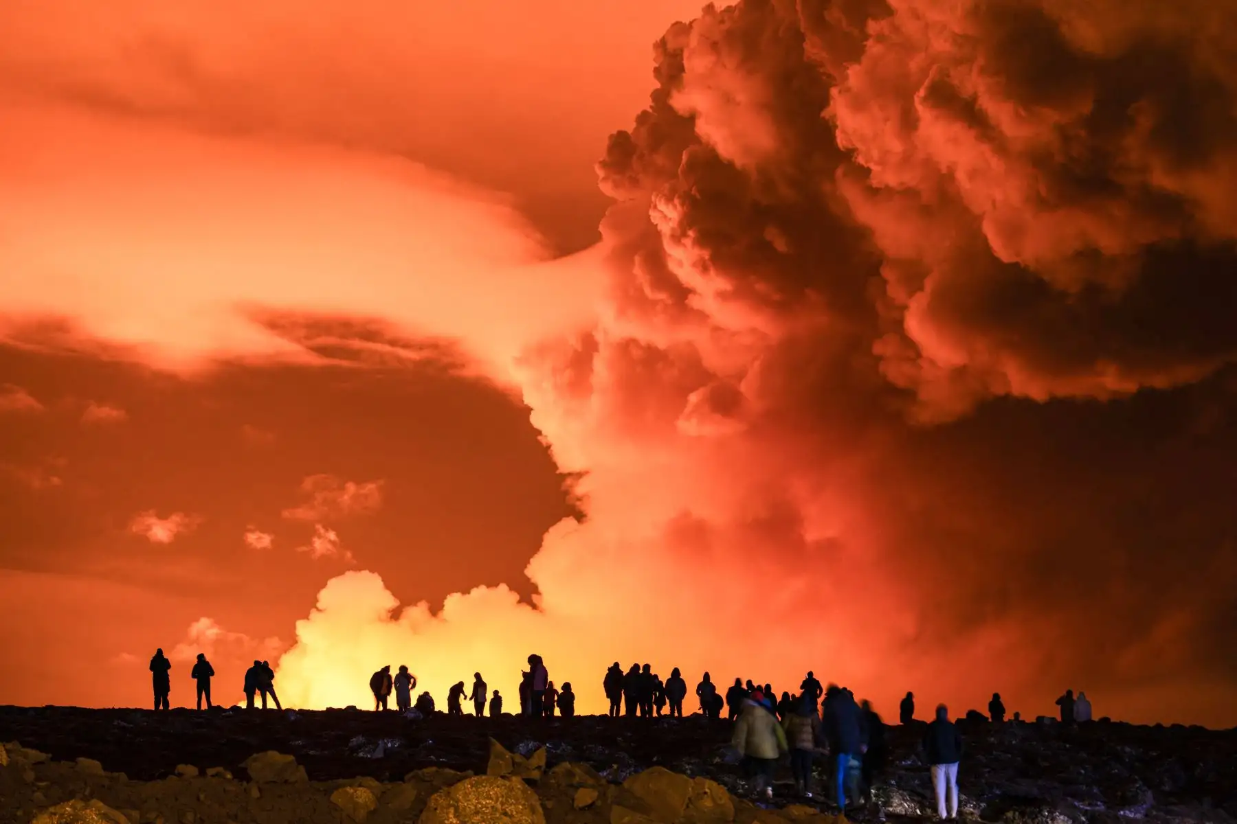 La gente se reúne para observar cómo la lava fundida fluye desde una fisura en la península de Reykjanes, al norte de la ciudad evacuada de Grindavik, en el oeste de Islandia. Foto: AFP