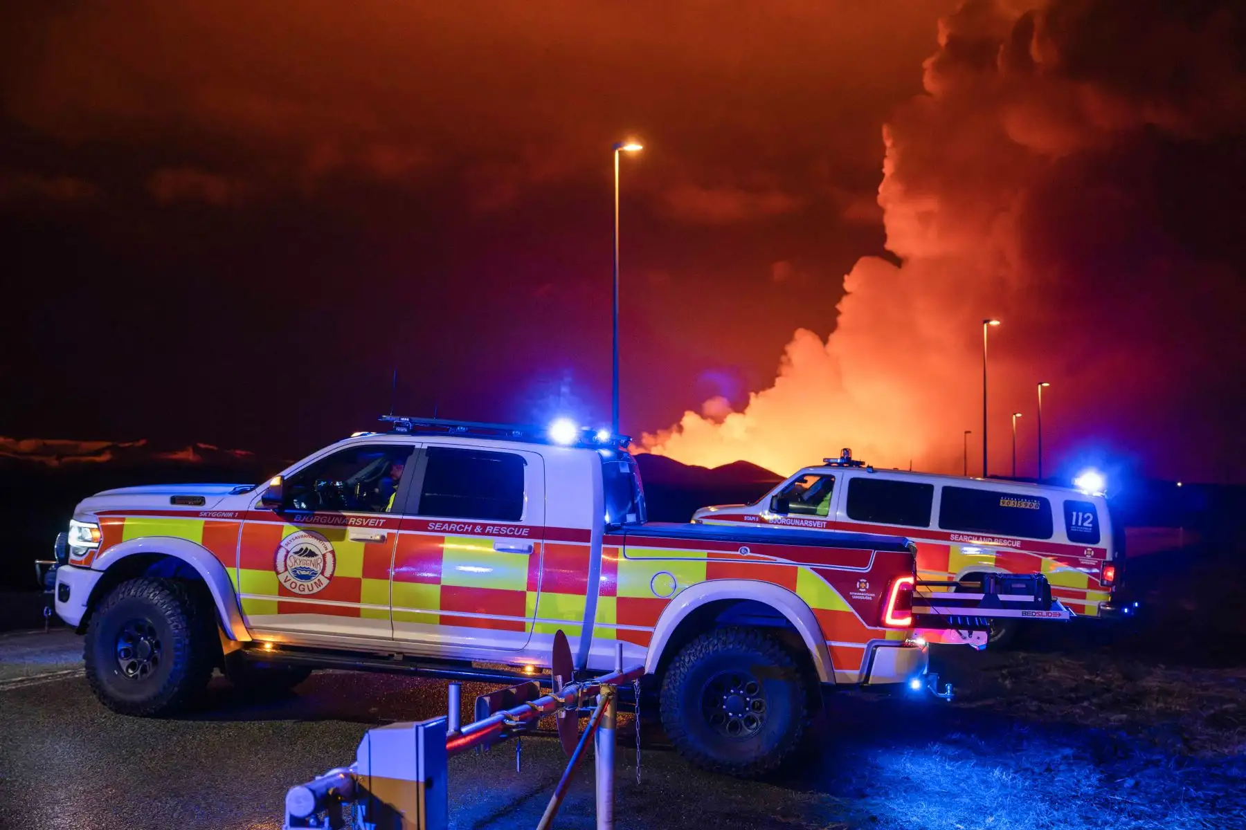 Se ven vehículos de emergencia mientras lava fundida sale de una fisura en la península de Reykjanes, al norte de la ciudad evacuada de Grindavik. Foto: AFP