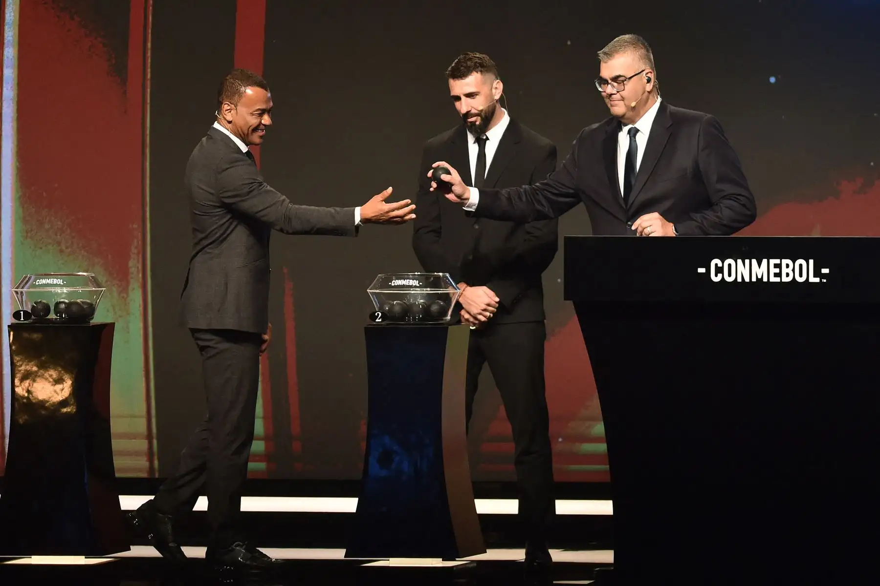 El Director de Competiciones de Clubes de la Conmebol, Frederico Nantes, es asistido por el exfutbolista brasileño Cafu  junto al delantero argentino Lucas Pratto durante el sorteo de la Copa Libertadores en la sede de la Conmebol en Luque, Paraguay.
Foto: AFP