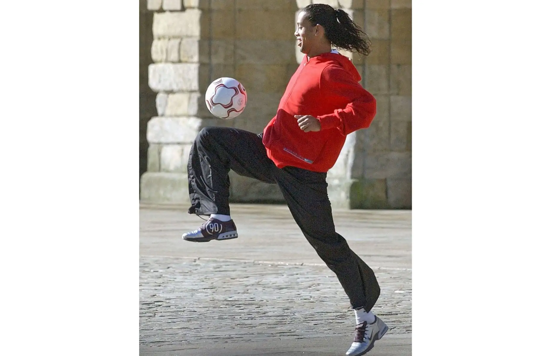El jugador brasileño del Barcelona Ronaldinho juega con un balón durante la grabación de un spot publicitario del Camino Santo de Santiago frente a la Catedral de Santiago de Compostela, el 1 de marzo de 2004. Foto: AFP