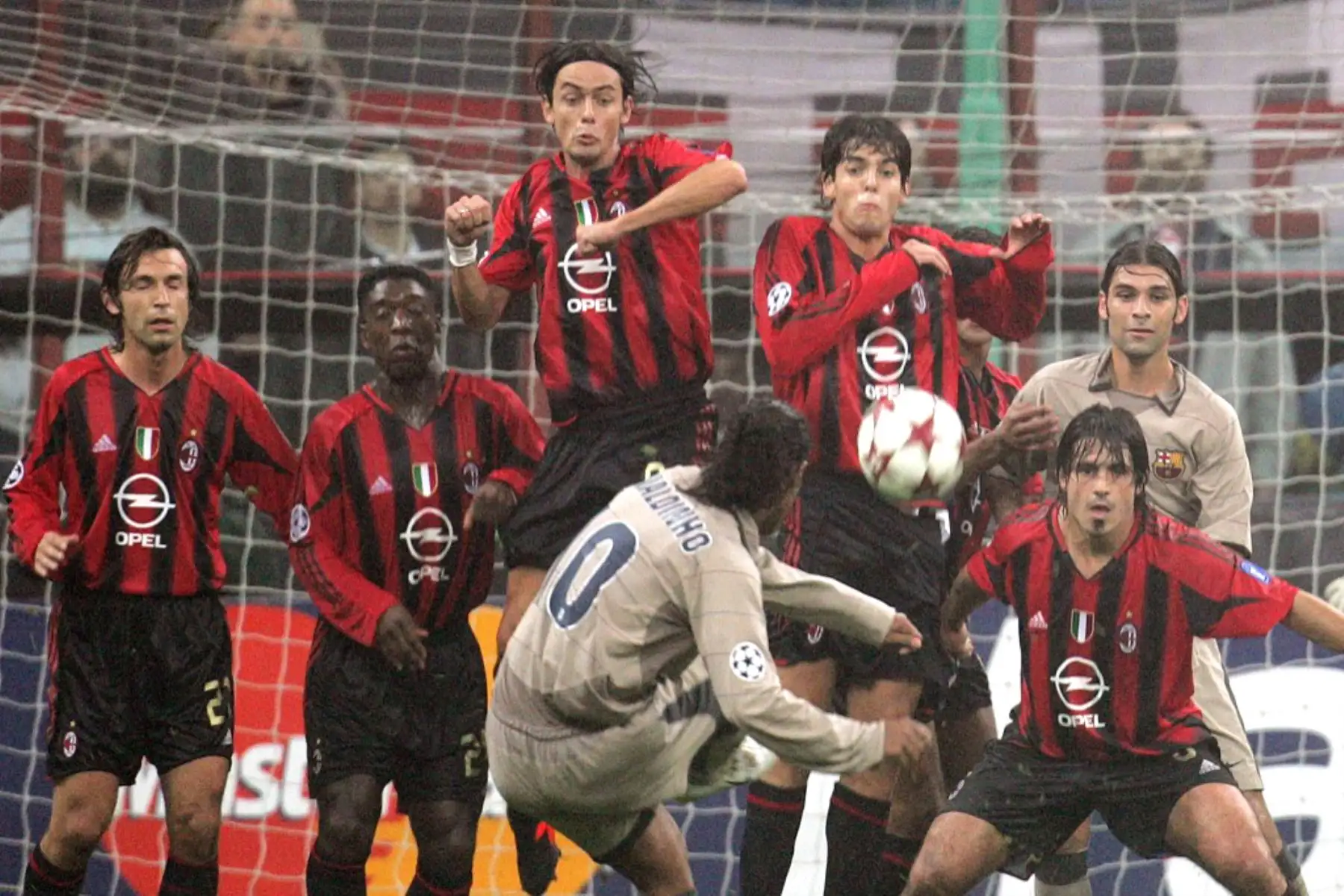 El delantero brasileño del Barcelona Ronaldinho dispara un tiro libre hacia la portería y los jugadores del AC Milan durante su partido de fútbol del grupo F de la Liga de Campeones contra el  AC Milan, en el estadio de San Siro de Milán el 20 de octubre de 2004. Foto: AFP