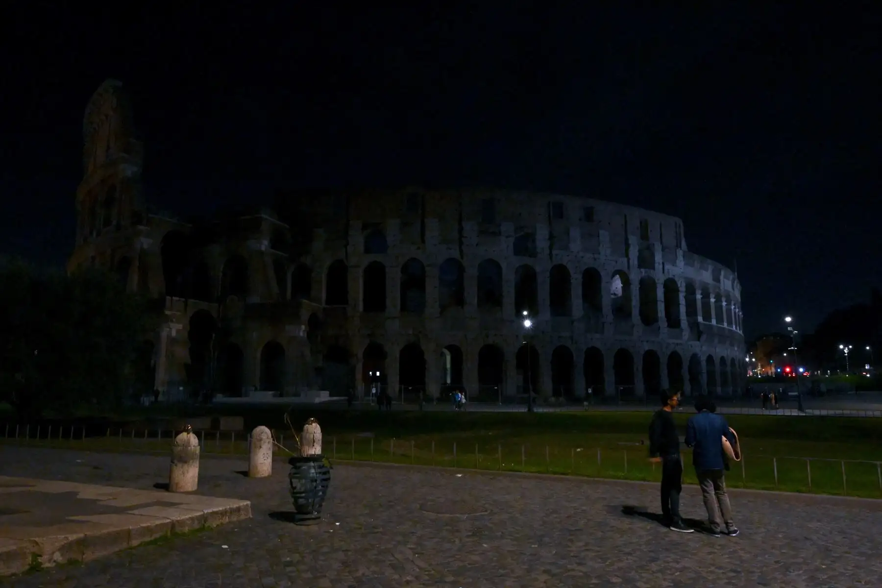 Peatones caminan junto al antiguo Coliseo, con las luces del monumento apagadas como parte de la iniciativa La Hora del Planeta, en Roma. Foto: AFP