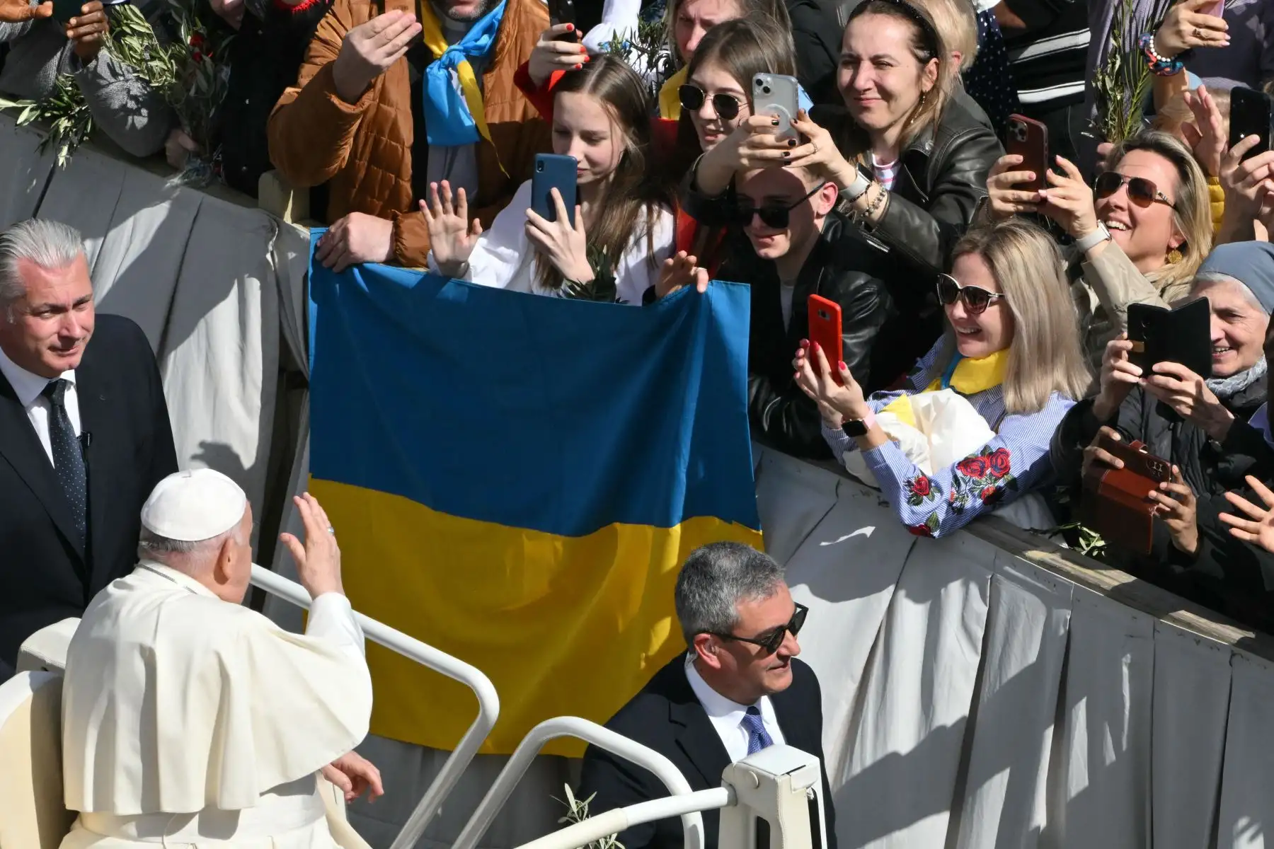 El Papa Francisco saluda a personas que sostienen una bandera ucraniana desde el papamóvil al final de la misa del Domingo de Ramos en la plaza de San Pedro en el Vaticano. Foto: ANDINA/AFP
