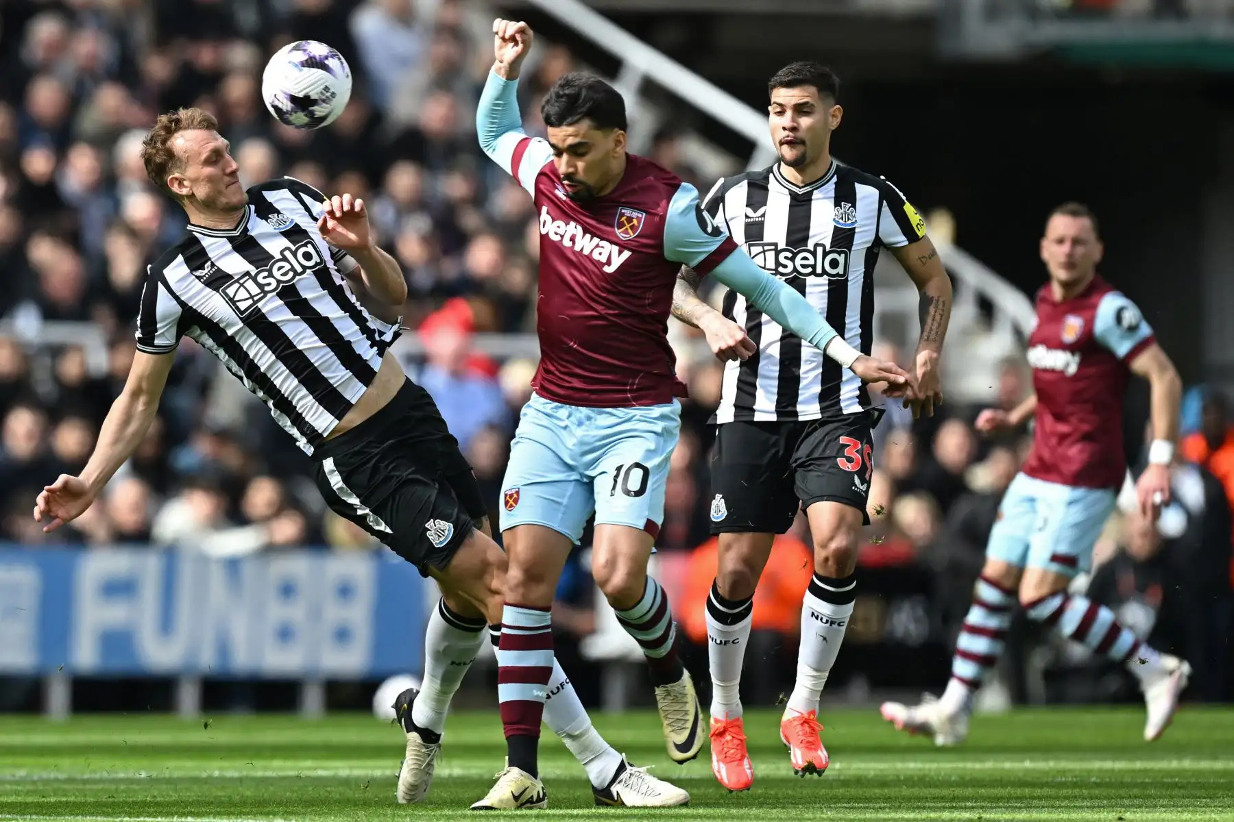 El centrocampista brasileño del West Ham United  Lucas Paqueta  compite con el defensor inglés del Newcastle United  Dan Burn y el centrocampista brasileño del Newcastle United  Bruno Guimaraes durante el partido de fútbol de la Liga Premier inglesa entre Newcastle United y West Ham United en St James