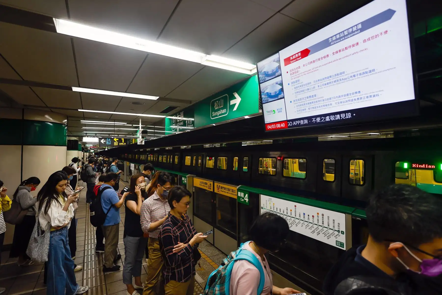 Los pasajeros esperan debajo de una pantalla que transmite un anuncio de suspensión del tren subterráneo luego de un terremoto de magnitud 7.4 cerca de Hualien, Taiwán. Foto: EFE.