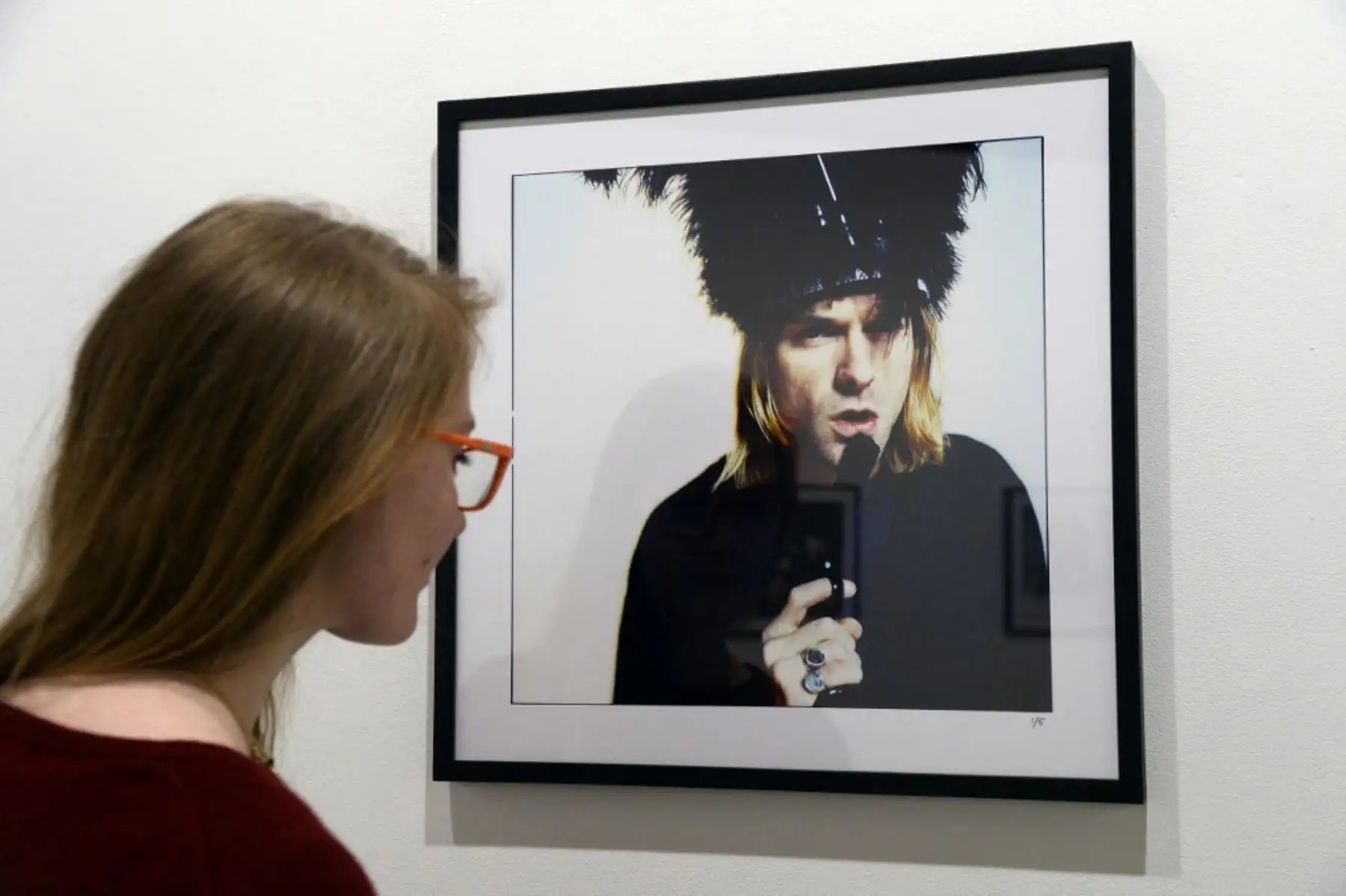 Una mujer mira una foto del fallecido cantante Kurt Cobain, posando con una pistola, como parte de la exposición "El último tiroteo" el 28 de marzo de 2014 en la galería Addict de París. Foto: AFP