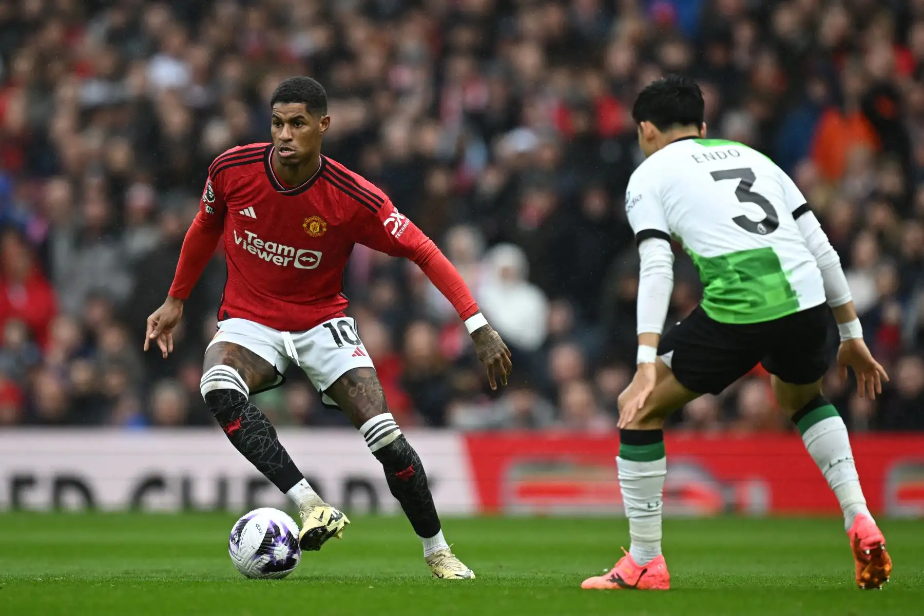 El delantero inglés del Manchester United  Marcus Rashford compite con el mediocampista japonés del Liverpool  Wataru Endo  durante el partido de fútbol de la Premier League inglesa entre Manchester United y Liverpool. Foto: ANDINA/ AFP