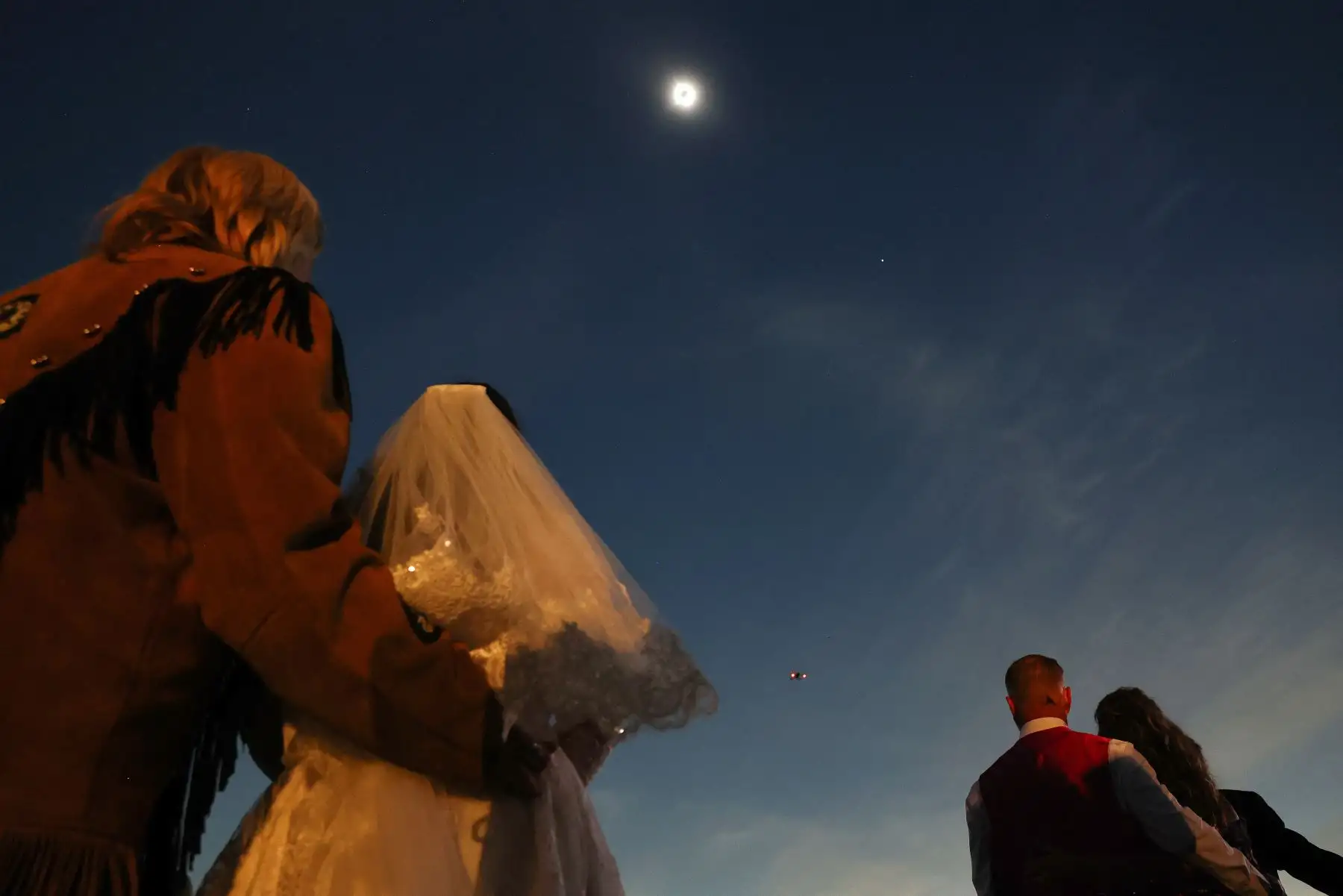 Parejas de novios ven el eclipse solar durante la totalidad en una boda masiva en el festival Eclipse Total del Corazón el 8 de abril de 2024 en Russellville, Arkansas. Foto: AFP