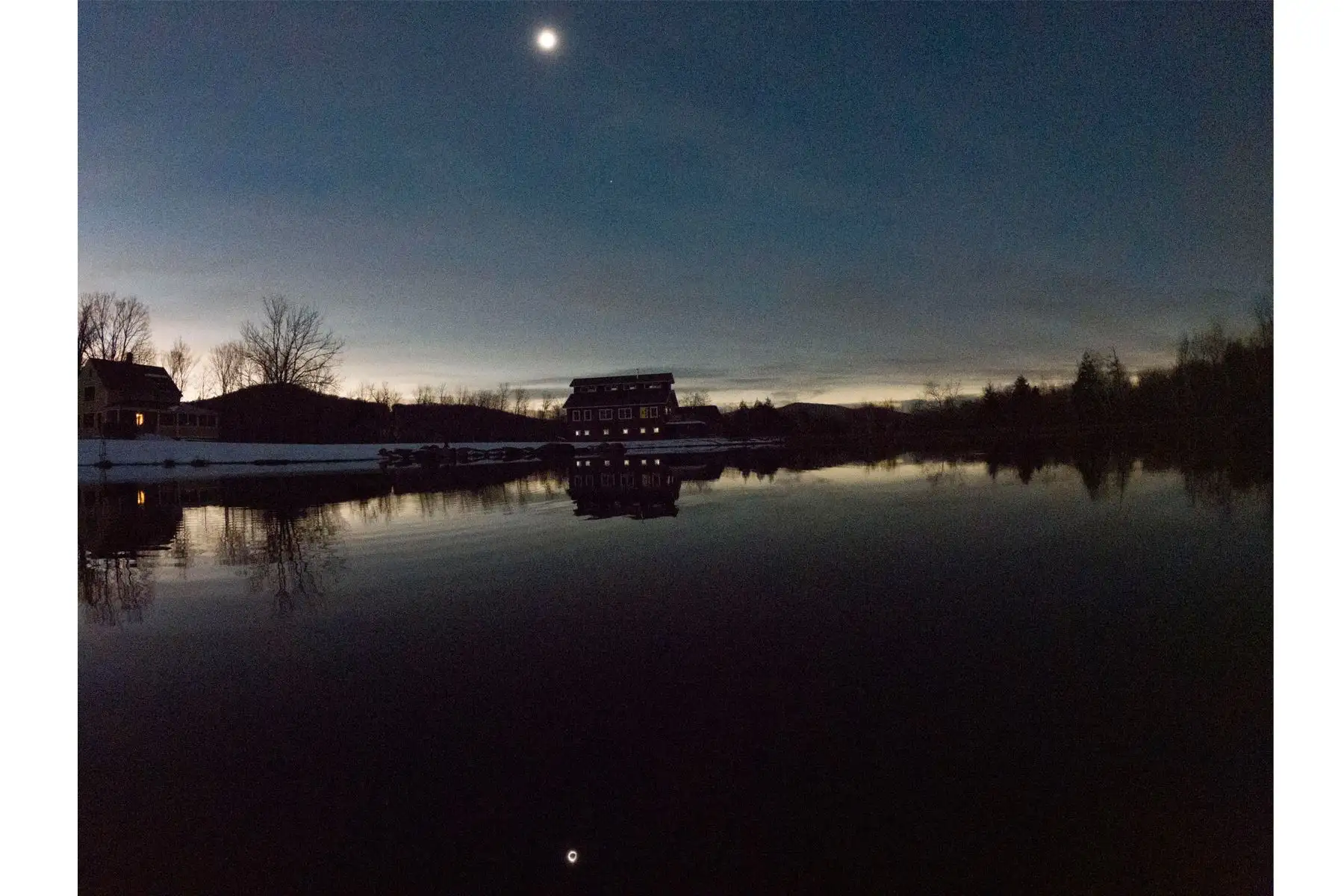 El eclipse solar total se refleja en un estanque sobre un granero en Huntington, Vermont, EE.UU., 08 de abril de 2024. Foto: EFE