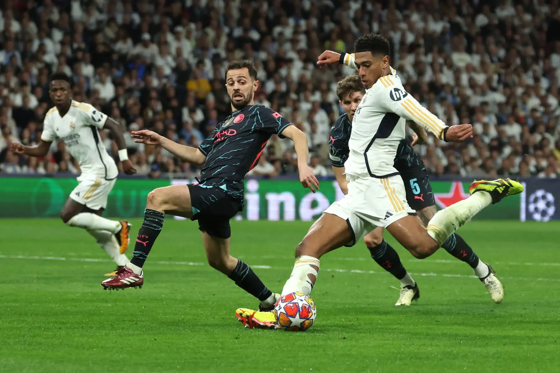 El centrocampista inglés del Real Madrid, Jude Bellingham  patea el balón junto al centrocampista portugués del Manchester City #20 Bernardo Silva  y el defensor inglés del Manchester City,  John Stones durante el partido de fútbol de ida de los cuartos de final de la Liga de Campeones de la UEFA entre el Real Madrid CF y el Manchester City en el estadio Santiago Bernabeu de Madrid.
Foto: AFP