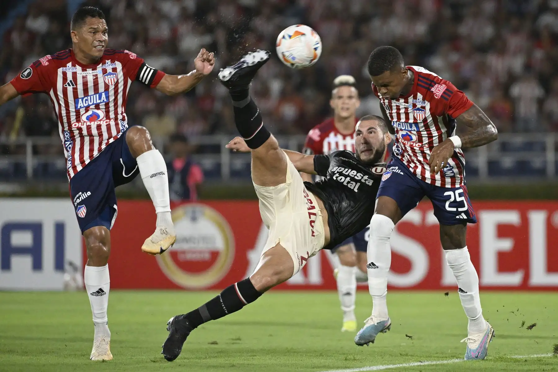 El defensor de Universitario Marcos Saravia  patea el balón entre el delantero de Junior Carlos Bacca y el mediocampista Carlos Cantillo durante el partido de fútbol de ida de la fase de grupos de la Copa Libertadores entre Junior de Colombia y Universitario de Perú en el Estadio Metropolitano Roberto Meléndez en Barranquilla.
Foto: AFP