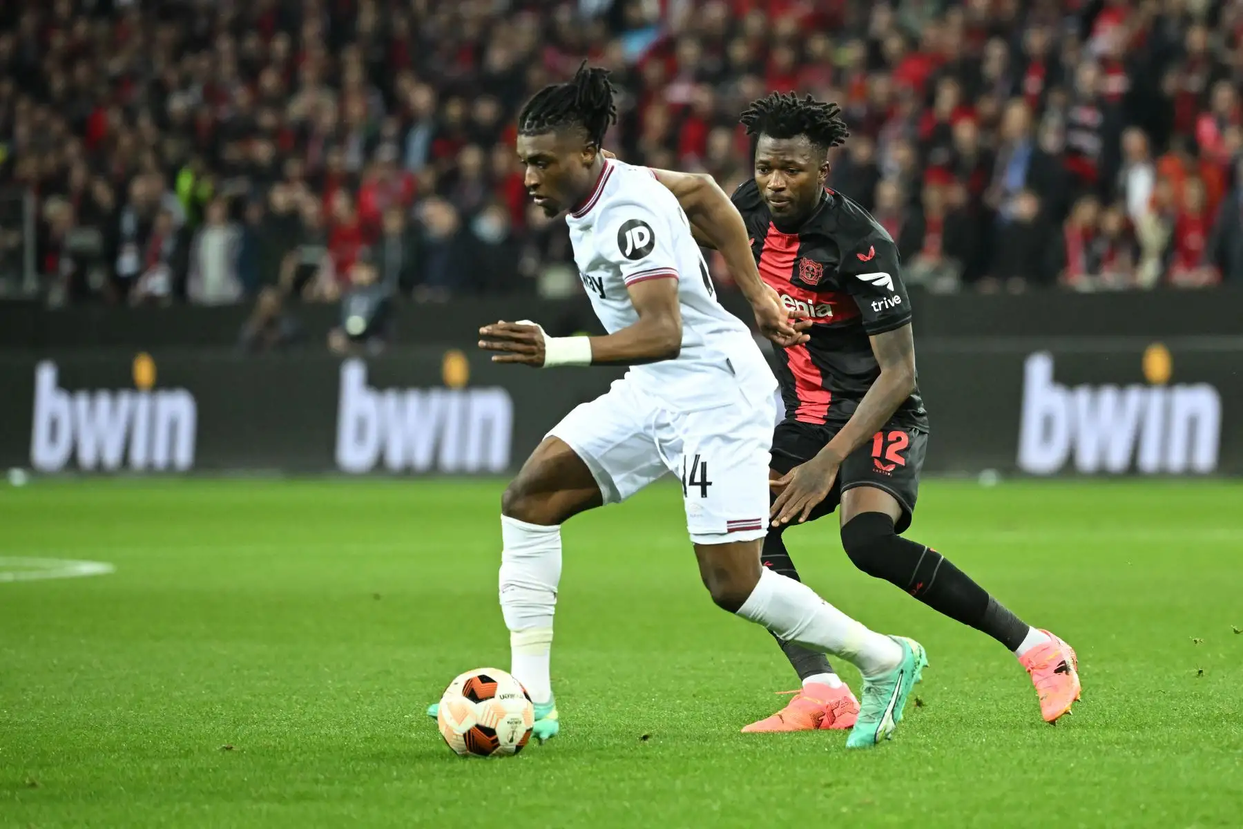El defensor burkinés del Bayer Leverkusen Edmond Tapsoba y el centrocampista ghanés del West Ham United Mohammed Kudus compiten por el balón durante el partido de fútbol de ida de los cuartos de final de la UEFA Europa League entre el Bayer 04 Leverkusen y el West Ham United FC en Leverkusen, oeste Alemania. Foto: ANDINA/AFP
