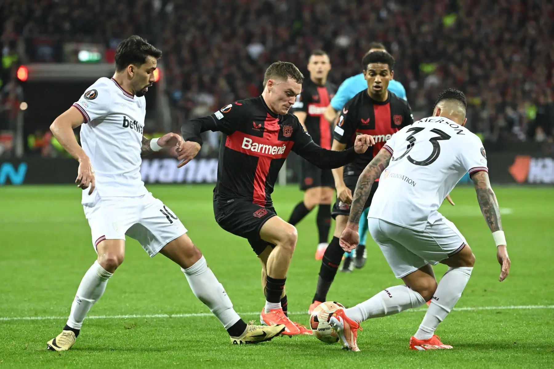 El centrocampista alemán del Bayer Leverkusen  Florian Wirtz compite por el balón con el centrocampista brasileño del West Ham United Lucas Paqueta  y el defensor italiano del West Ham United Emerson durante el partido de fútbol de ida de los cuartos de final de la UEFA Europa League entre Bayer 04 Leverkusen y West Ham United FC en Leverkusen, oeste de Alemania. Foto: ANDINA/AFP