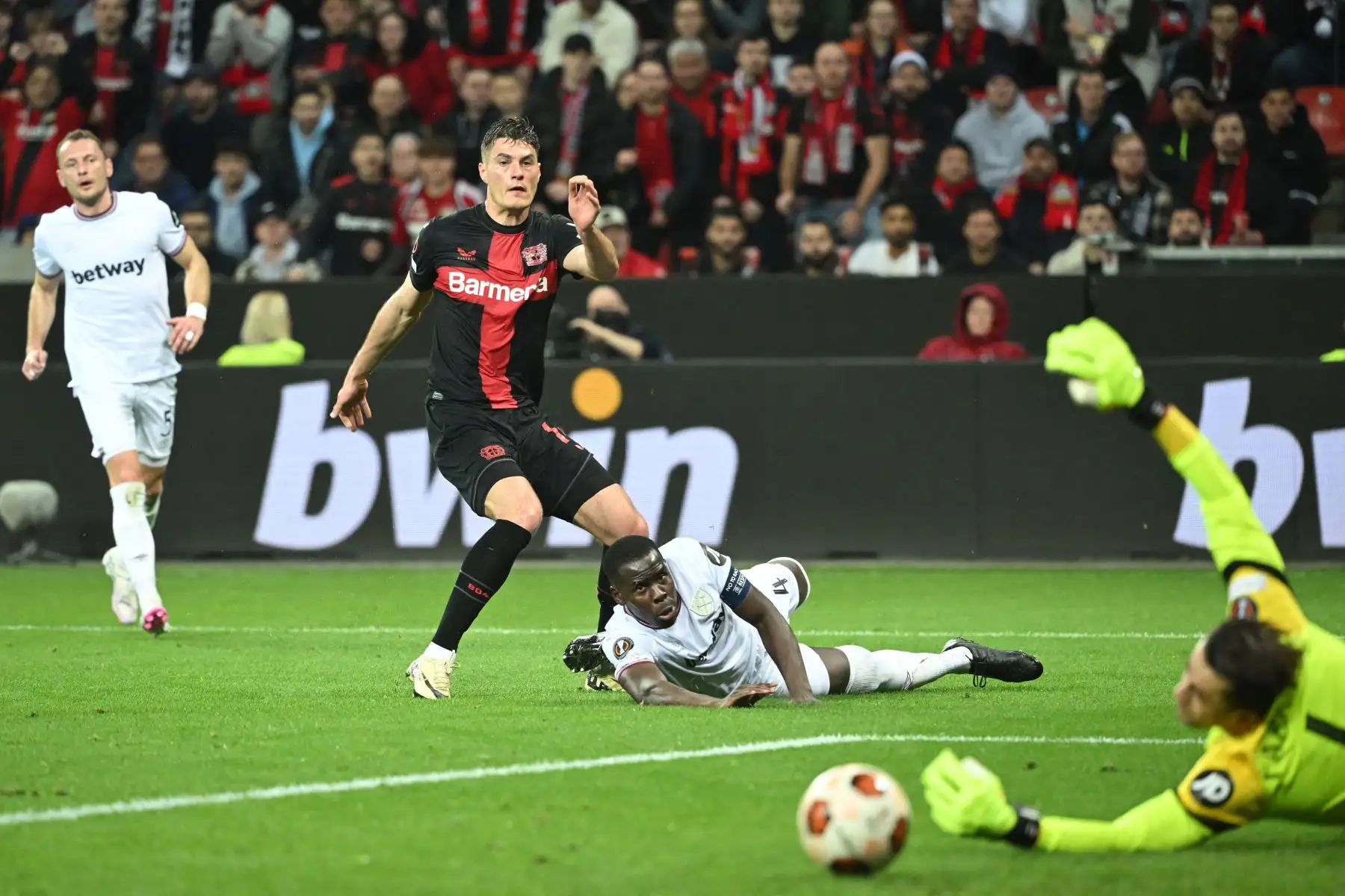 El delantero checo del Bayer Leverkusen Patrik Schick hace un intento de gol pasado el centrocampista ghanés del West Ham United  Mohammed Kudus y el portero polaco del West Ham United Lukasz Fabianski  durante el partido de ida de los cuartos de final de la UEFA Europa League Partido entre Bayer 04 Leverkusen y West Ham United FC en Leverkusen, oeste de Alemania. Foto: ANDINA/AFP