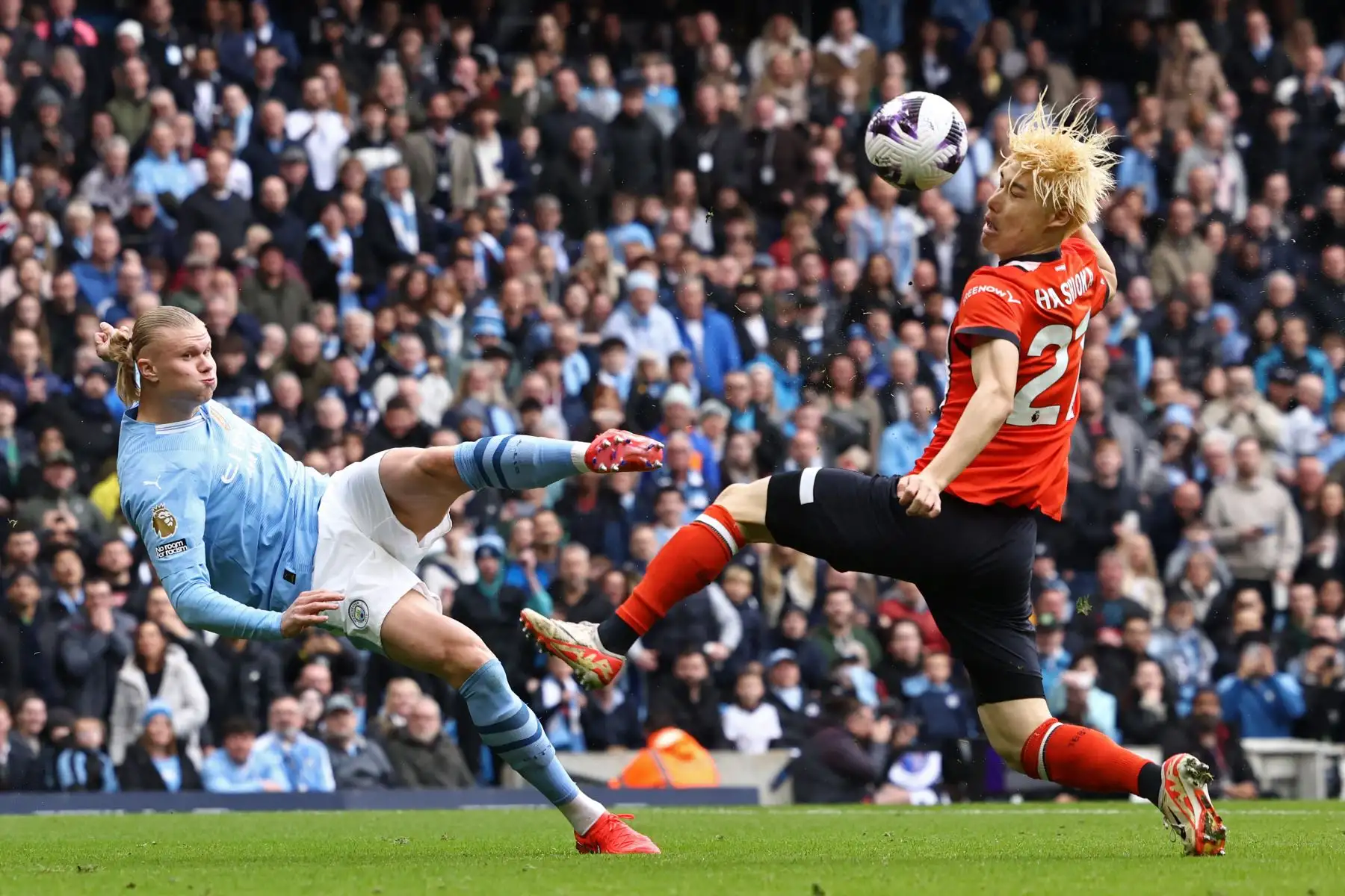 El delantero noruego del Manchester City Erling Haaland  ve su disparo desviado hacia la red por el defensor japonés del Luton Town Daiki Hashioka  para un gol en propia meta durante el partido de fútbol de la Liga Premier inglesa entre Manchester City y Luton Town en el Estadio Etihad en Manchester, noroeste de Inglaterra. Foto: ANDINA/AFP