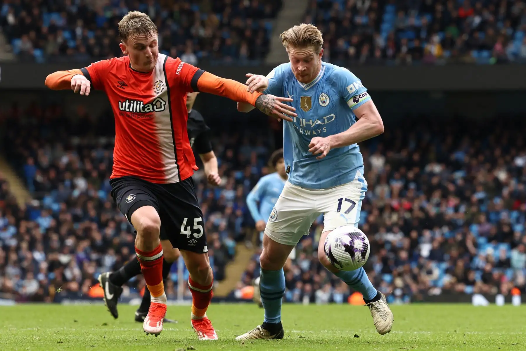 El centrocampista inglés de Luton Town Alfie Doughty  compite con el centrocampista belga de Manchester City  Kevin De Bruyne durante el partido de fútbol de la Liga Premier inglesa entre Manchester City y Luton Town en el estadio Etihad de Manchester, noroeste de Inglaterra. Foto: ANDINA/AFP