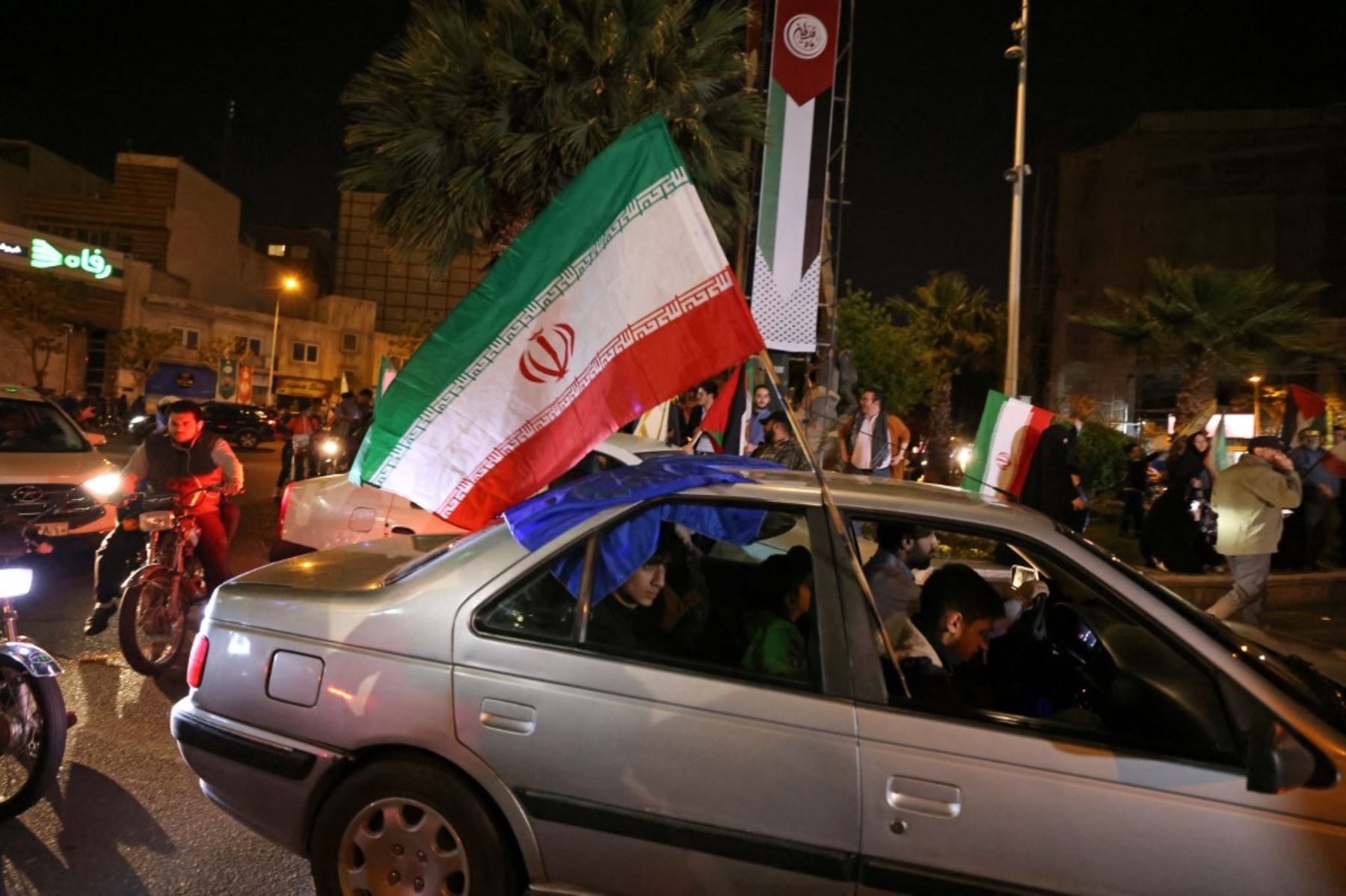 Manifestantes ondean la bandera de Irán y las banderas palestinas mientras se reúnen en la Plaza Palestina en Teherán después de que Irán lanzara un ataque con aviones no tripulados y misiles contra Israel. Foto: AFP