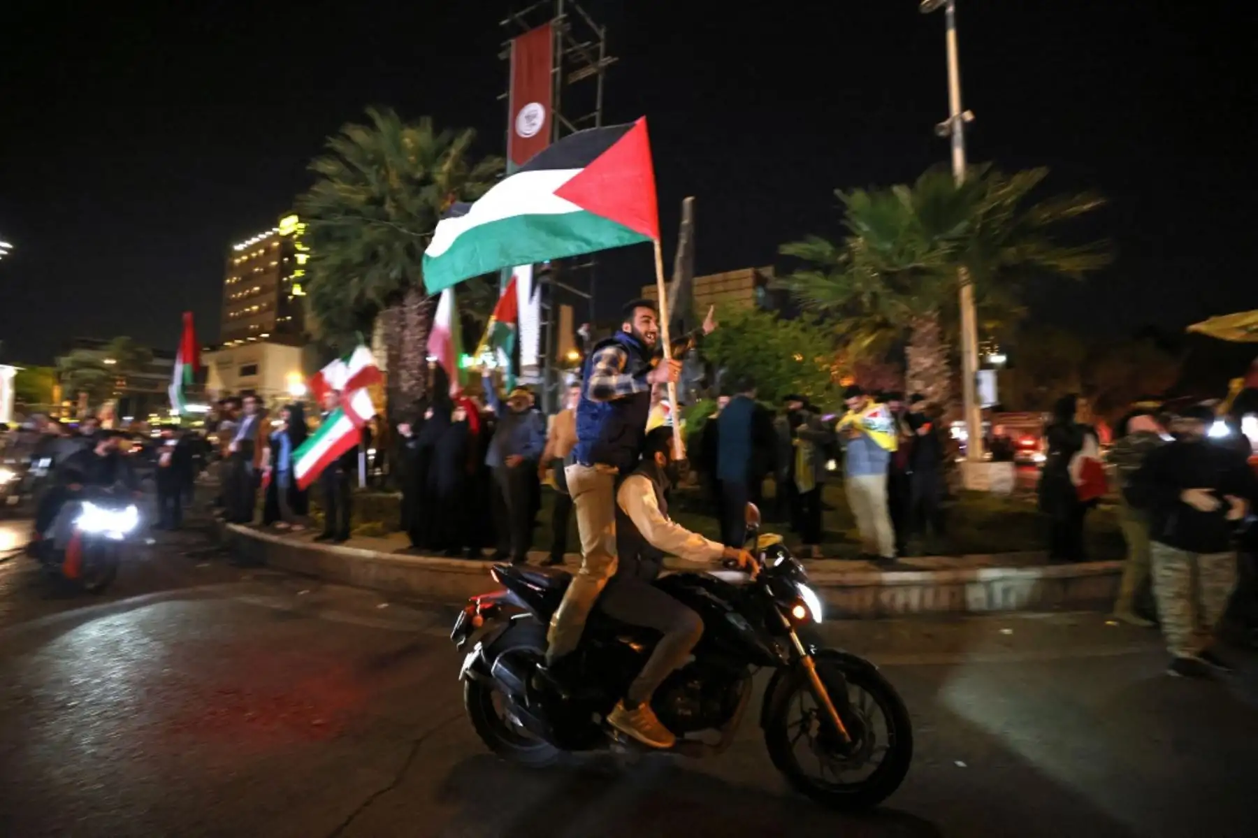 Manifestantes ondean la bandera de Irán y las banderas palestinas mientras se reúnen en la Plaza Palestina en Teherán después de que Irán lanzara un ataque con aviones no tripulados y misiles contra Israel. Foto: AFP