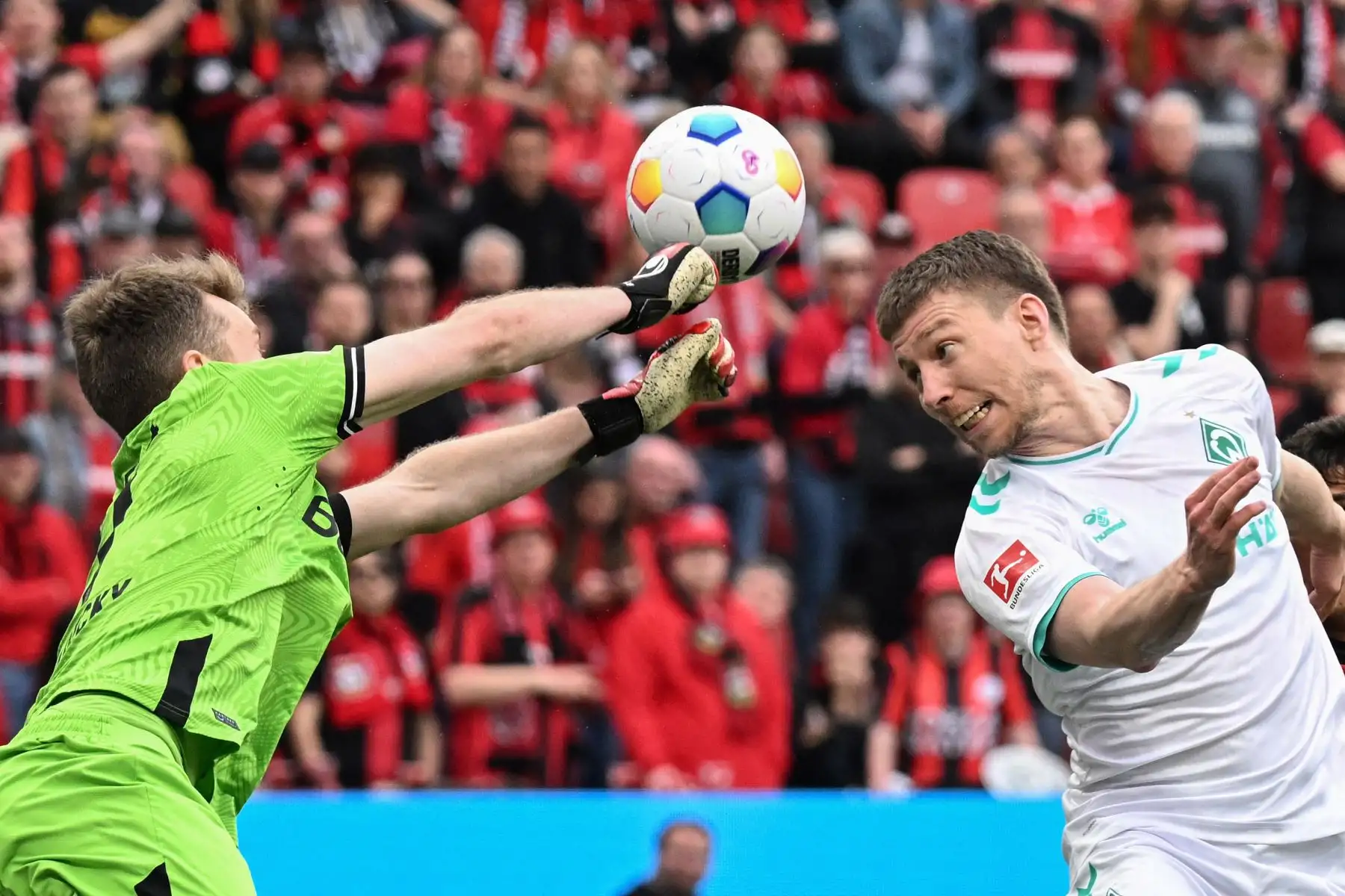El defensor argentino de Bremen Julian Malatini intenta anotar un cabezazo ante el portero finlandés del Bayer Leverkusen Lukas Hradecky durante el partido de fútbol de la primera división alemana de la Bundesliga Bayer 04 Leverkusen contra Werder Bremen. 
Foto: ANDINA/AFP
