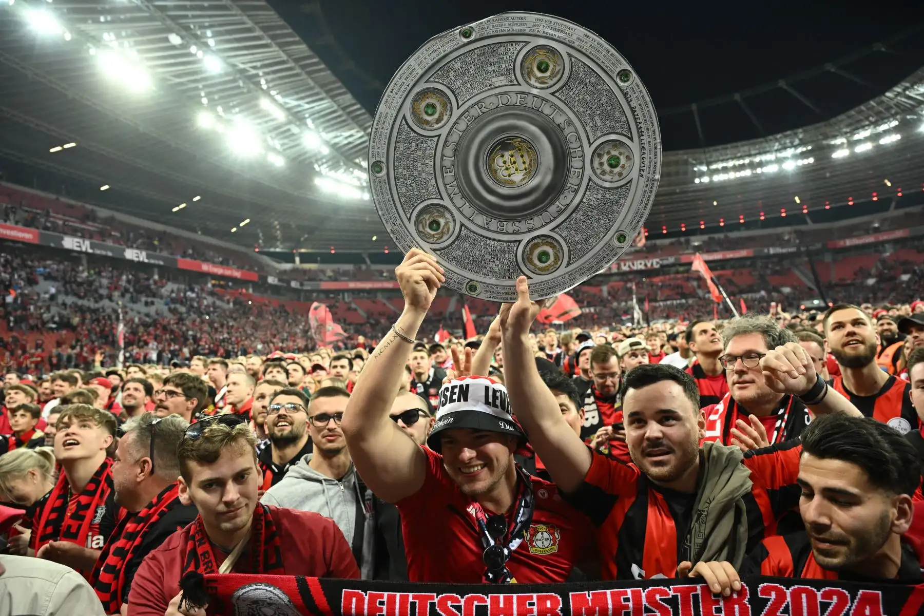 Los fans de Bayer Leverkusen celebran con una maqueta del trofeo de la Bundesliga después del partido de fútbol alemán de primera división de la Bundesliga Bayer 04 Leverkusen contra Werder Bremen en Leverkusen, Alemania occidental. Bayer Leverkusen fue coronado campeón de la Bundesliga 2023-24. Foto: ANDINA/ AFP