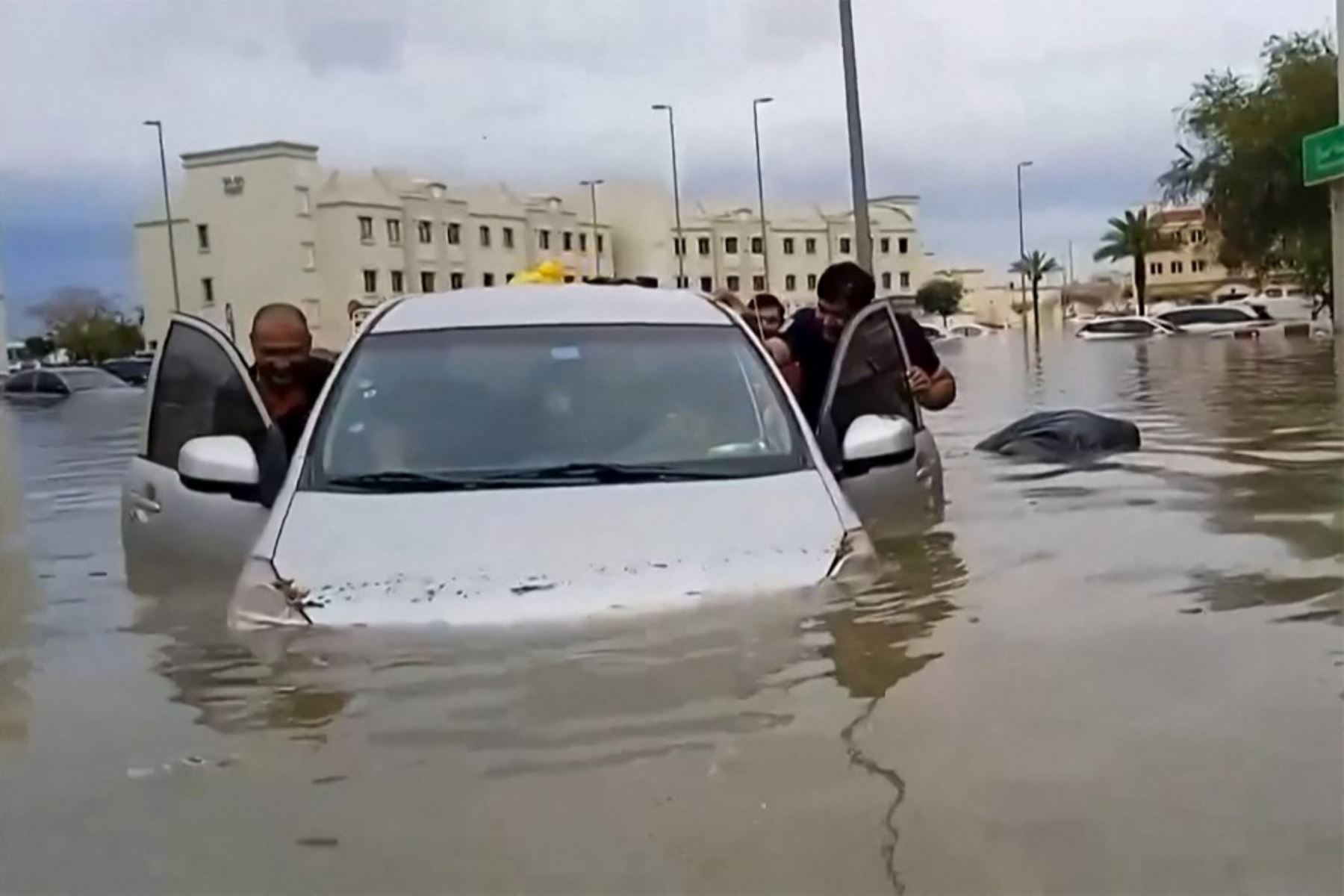 personas empujan un coche varado por una calle inundada en Dubai el 16 de abril de 2024. Dubai, el centro financiero de Oriente Medio, quedó paralizado por las lluvias torrenciales que provocaron inundaciones en los Emiratos Árabes Unidos y Bahréin y dejaron 18 muertos en Omán en abril.  Foto: AFP