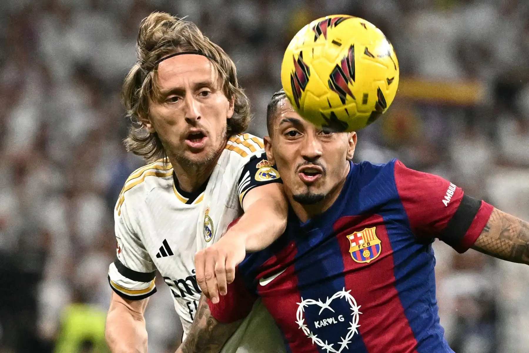 El delantero brasileño del Barcelona, Raphinha, compite con el mediocampista croata del Real Madrid, Luka Modric, durante el partido de fútbol de la liga española entre el Real Madrid FC y el FC Barcelona en el estadio Santiago Bernabeu de Madrid el 21 de abril de 2024. Foto: AFP
