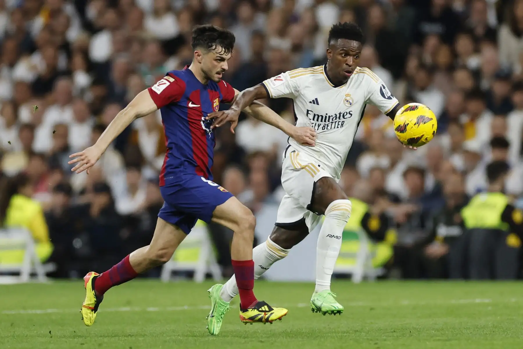El centrocampista español del Barcelona, Pedri, y el delantero brasileño del Real Madrid, Vinicius Junior, compiten por el balón durante el partido de fútbol de la liga española entre el Real Madrid FC y el FC Barcelona en el estadio Santiago Bernabeu de Madrid el 21 de abril de 2024. Foto: AFP