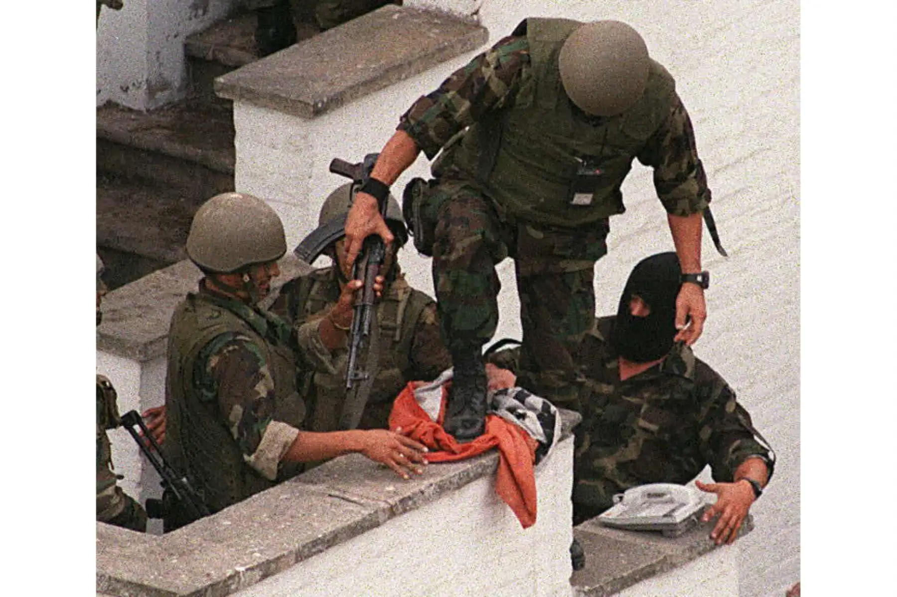 Comandos Chavín de Huántar pisotean una de las banderas del grupo terrorista del MRTA en el techo de la residencia del embajador japonés en Lima. Foto: AFP