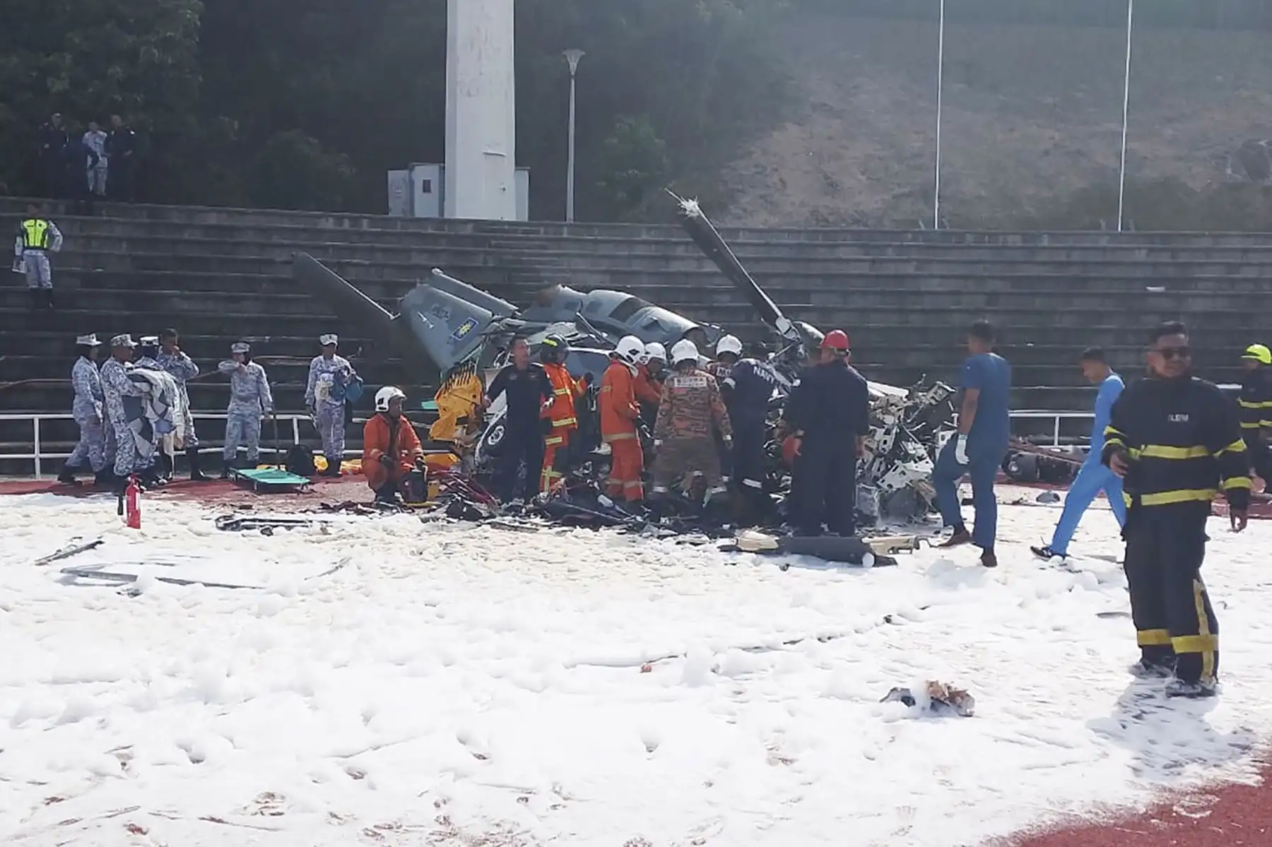 Fotografía proporcionada por el Departamento de Bomberos y Rescate de Perak muestra a oficiales del Departamento de Bomberos y Rescate de Malasia en el lugar donde dos helicópteros se estrellaron durante un ensayo, en la base de la Marina Real de Malasia. Foto: AFP