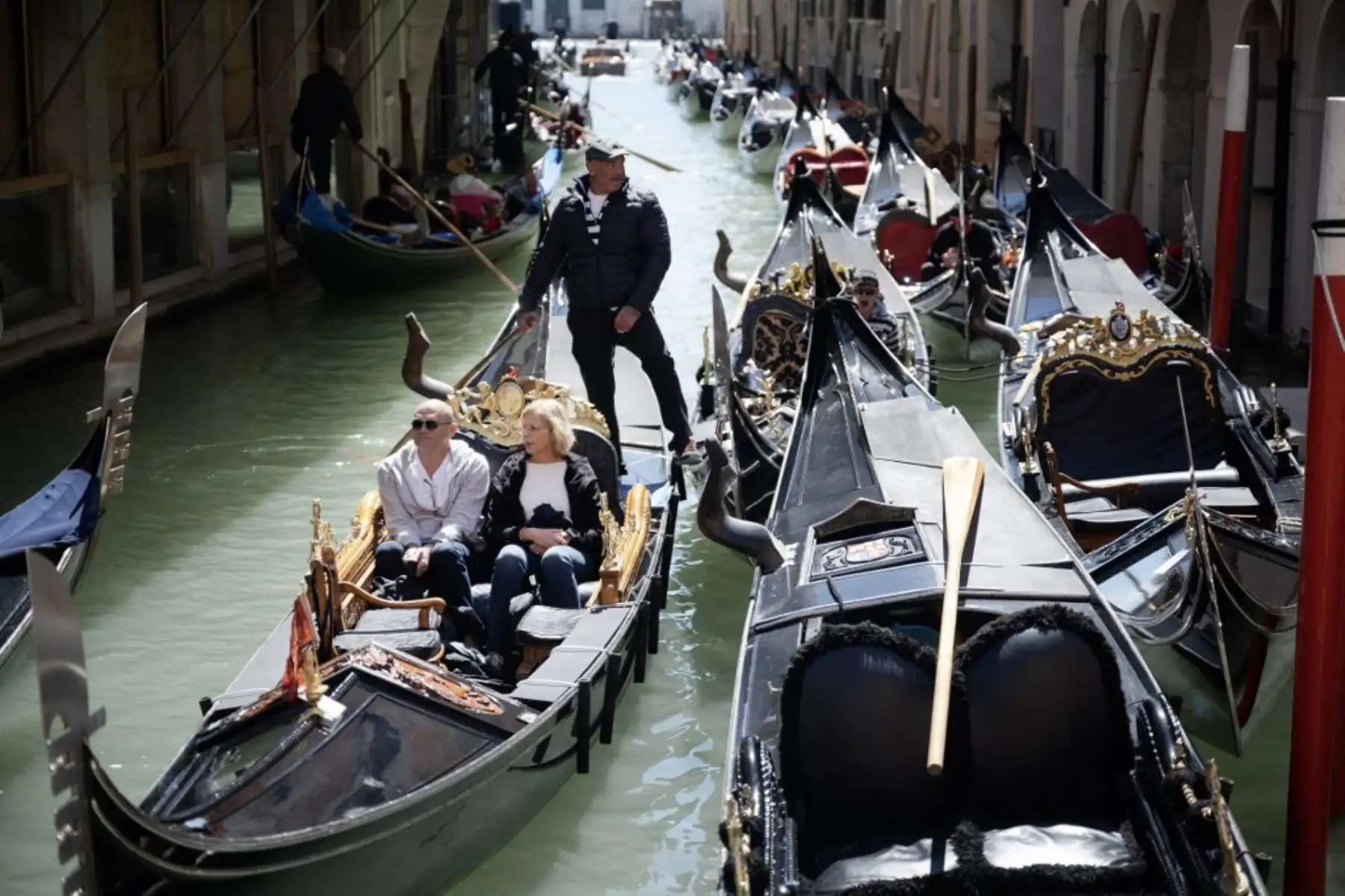 Un gondolero navega con dos clientes cerca de la Plaza de San Marcos en Venecia, el 25 de abril de 2024. La nueva estrategia para reducir el número de turistas que visitan este sitio declarado Patrimonio de la Humanidad por la UNESCO exige que los excursionistas paguen un billete de cinco euros para entrar a la ciudad histórica. centro y comenzará el 25 de abril. Foto: AFP