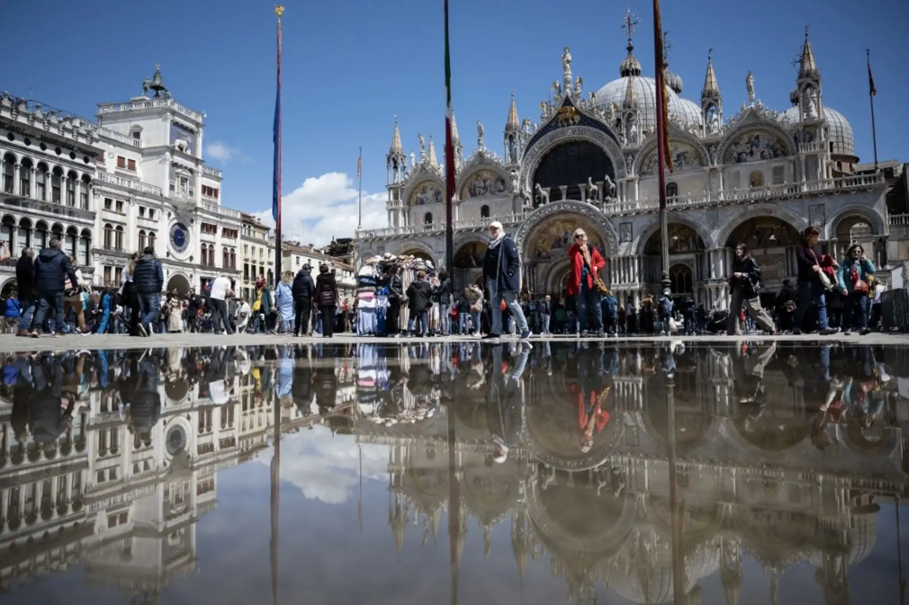 Esta fotografía tomada el 25 de abril de 2024 muestra una vista de la Plaza de San Marcos con la Basílica reflejada en un charco en Venecia, el 25 de abril de 2024. La nueva estrategia para reducir el número de turistas que visitan este sitio declarado Patrimonio de la Humanidad por la UNESCO exige un día -Los viajeros deberán pagar un billete de cinco euros para acceder al centro histórico de la ciudad y comenzará el 25 de abril. Foto: AFP