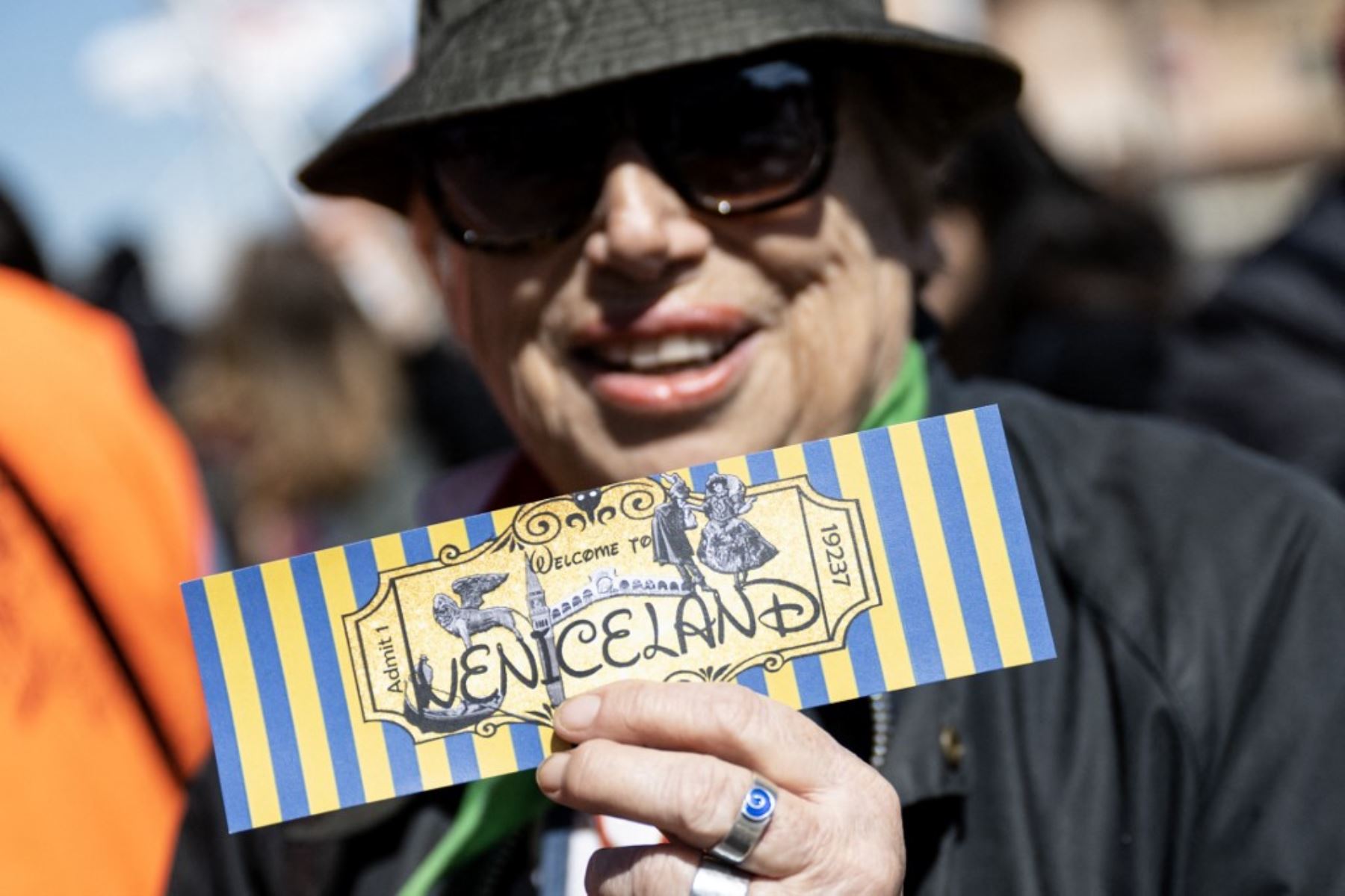 Una mujer sostiene un billete que dice "Bienvenidos a Venecialandia". Foto: AFP