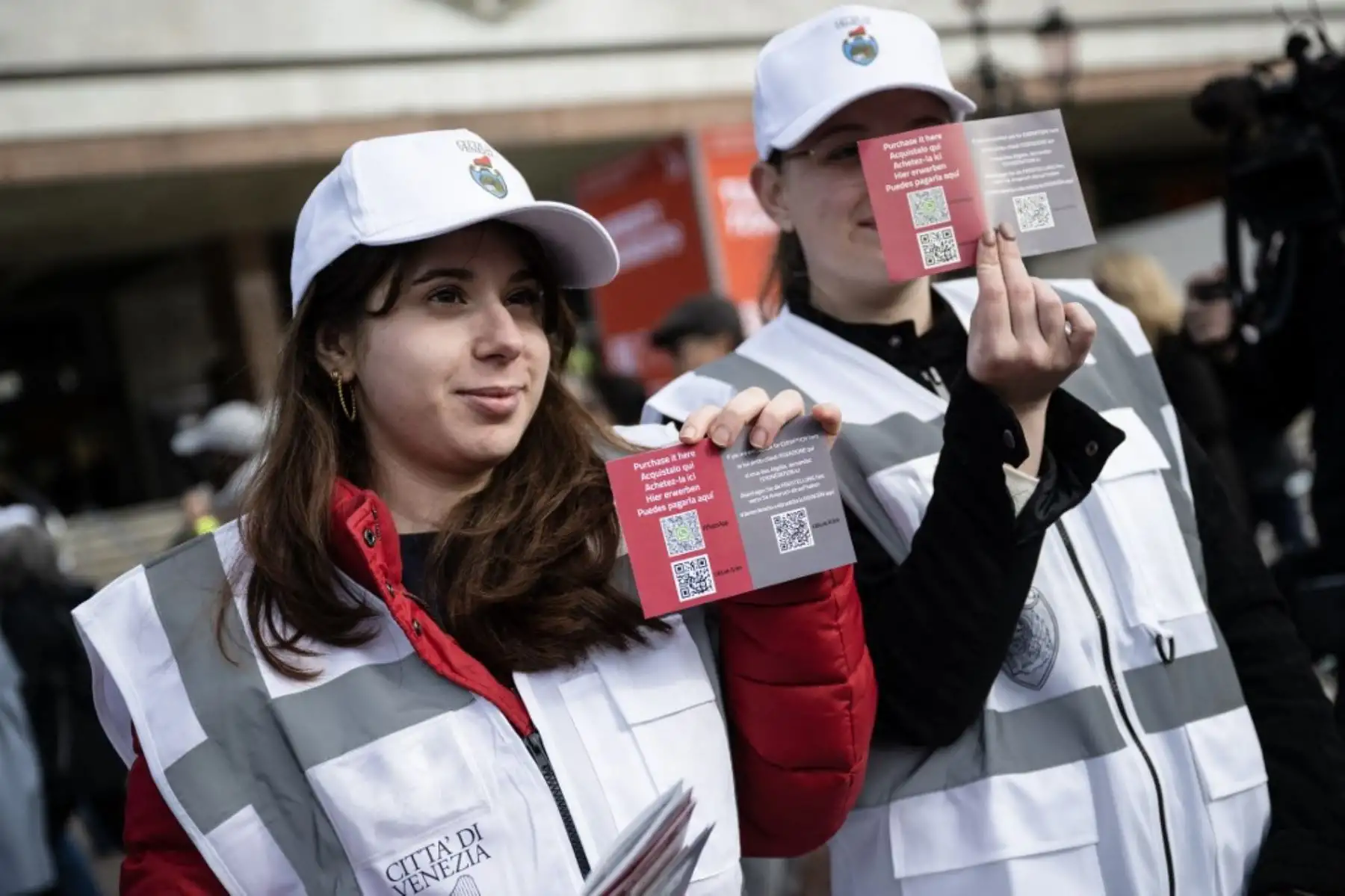 Trabajadores municipales de Venecia muestran postales informativas con código QR para comprar el billete de entrada a la ciudad, frente a la estación de tren de Santa Lucía mientras esperan para comprar los billetes, ya que los visitantes que acceden a este sitio declarado Patrimonio de la Humanidad por la UNESCO. Foto: AFP