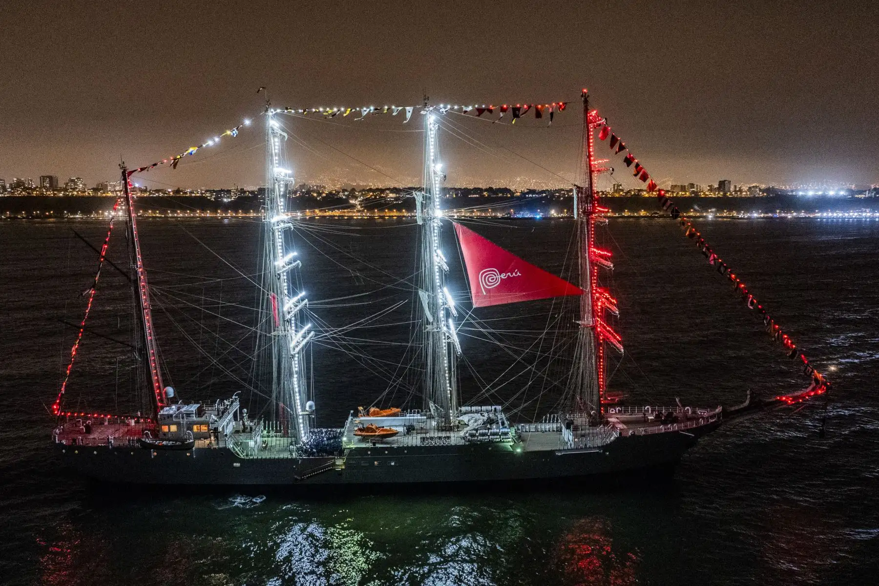 El Buque escuela B.A.P. Unión luce imponente frente a la costa de Chorrillos iluminado de rojo y blanco. Un gran espectáculo de fuegos artificiales le dio la bienvenida tras recorrer 36,400 millas náuticas y 317 días de viaje. Foto: Cortesía/Cristian Olea