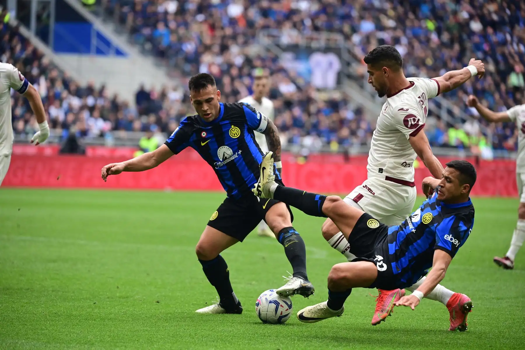 El delantero argentino del Inter de Milán Lautaro Martínez y el delantero chileno del Inter de Milán  Alexis Sánchez luchan por el balón con el defensor marroquí del Torino Adam Masina durante el partido de fútbol de la Serie A italiana entre el Inter de Milán y el Torino. Foto: ANDINA/AFP