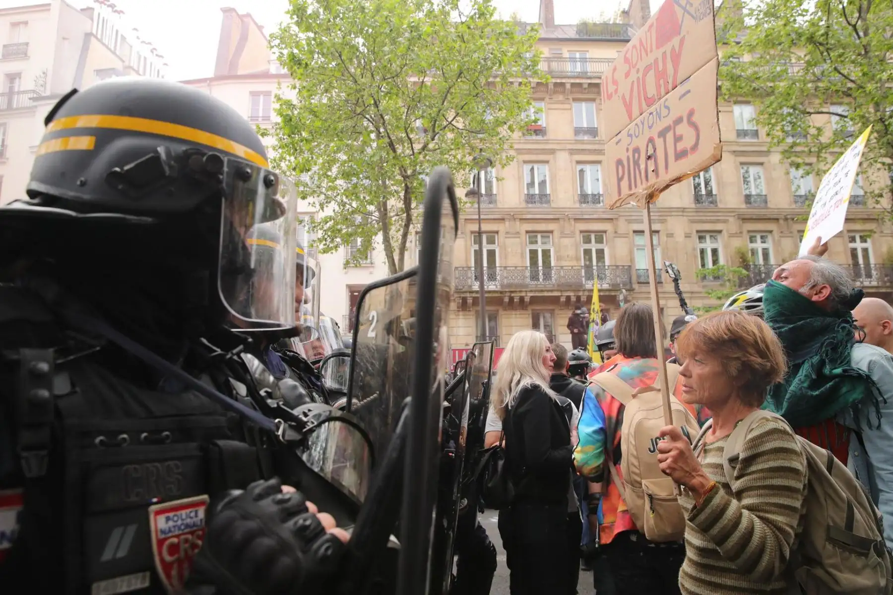 Una mujer sostiene una pancarta en la que se puede leer "Ellos son Vichy. Seamos piratas" durante la manifestación anual para celebrar el Día Internacional del Trabajo, este miércoles en París. Los sindicatos franceses reivindican en esta jornada la mejora de las condiciones de vida, el aumento de los salarios, la defensa de los servicios públicos y la implantación de una paz justa y duradera. EFE/Teresa Suarez