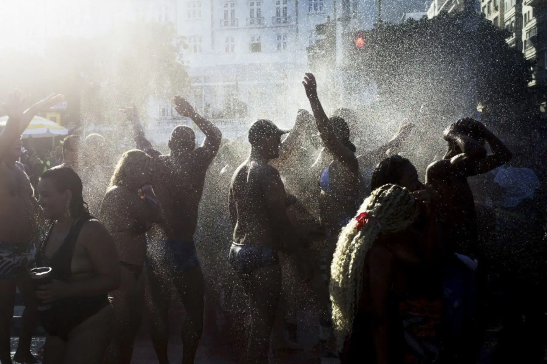 Los fanáticos de la estrella del pop estadounidense Madonna cantan y bailan mientras los bomberos rocían agua para refrescar al público en la playa de Copacabana antes de un mega concierto gratuito para cerrar su gira 