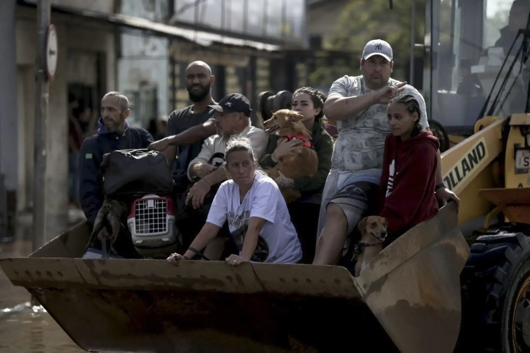 Personas son transportadas en una retroexcavadora luego de ser rescatadas en el barrio Sarandí en Porto Alegre, estado de Rio Grande do Sul, Brasil, el 5 de mayo de 2024. El desafío es titánico y contrarreloj: autoridades y vecinos intentan evitar una tragedia aún mayor que la ya vivida en el estado brasileño de Rio Grande do Sul, donde 66 personas murieron y 80.000 fueron desplazadas por las inundaciones, según las autoridades. Foto: AFP