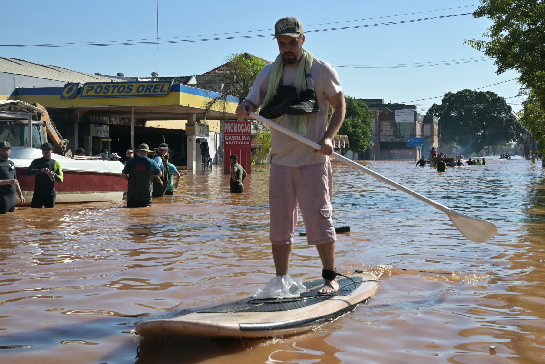 Un hombre navega en una tabla de surf tras las inundaciones provocadas por las fuertes lluvias en el barrio de Sarandí, Porto Alegre, estado de Rio Grande do Sul, en Brasil, el 6 de mayo de 2024. Foto: AFP