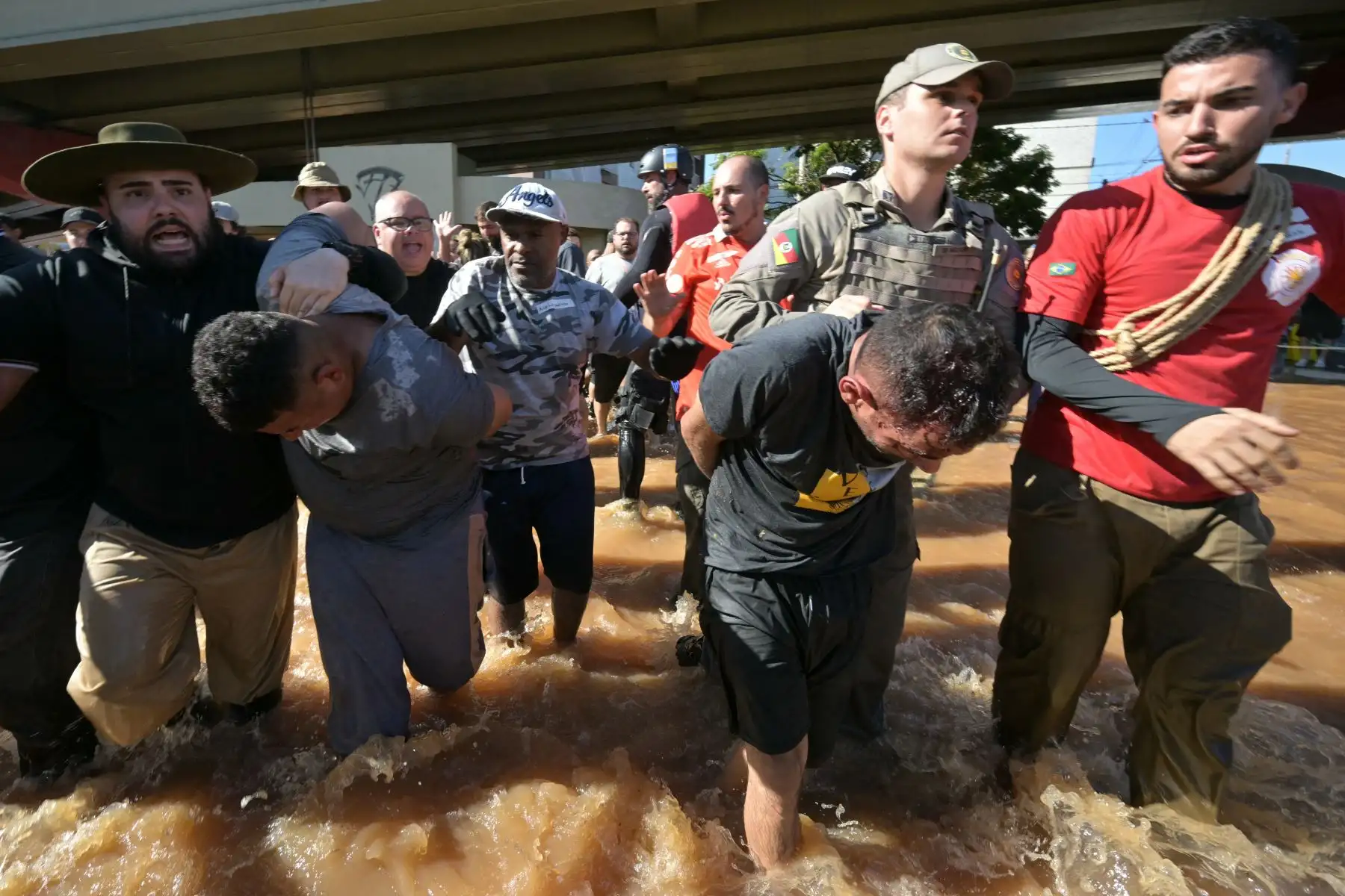 Miembros de la policía arrestan a dos hombres que presuntamente estaban robando casas tras las inundaciones provocadas por las fuertes lluvias en el barrio de Sarandí, Porto Alegre, estado de Rio Grande do Sul, en Brasil, el 6 de mayo de 2024. Los rescatistas rastrean los edificios de Porto Alegre en busca de habitantes atrapados en apartamentos o en tejados. Foto: AFP
