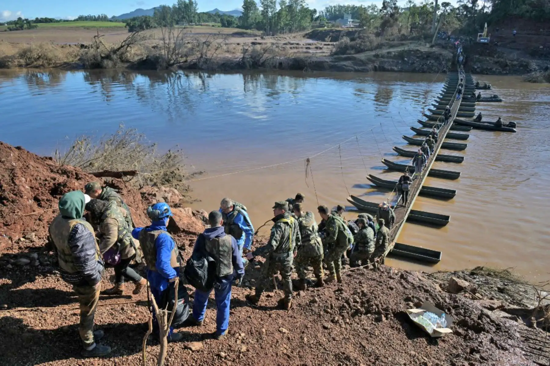 La gente camina en el paso de peatones de Arroio do Meio a Lajeado, sobre el río Forquilha, desde que el puente se cayó durante las recientes inundaciones, en el estado de Rio Grande do Sul, Brasil. Foto: AFP