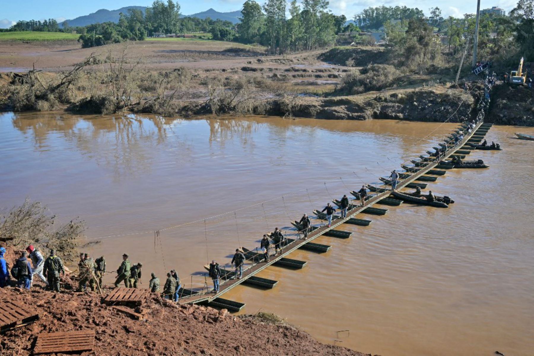 La gente camina en el paso de peatones de Arroio do Meio a Lajeado, sobre el río Forquilha, desde que el puente se cayó durante las recientes inundaciones, en el estado de Rio Grande do Sul, Brasil. Foto: AFP