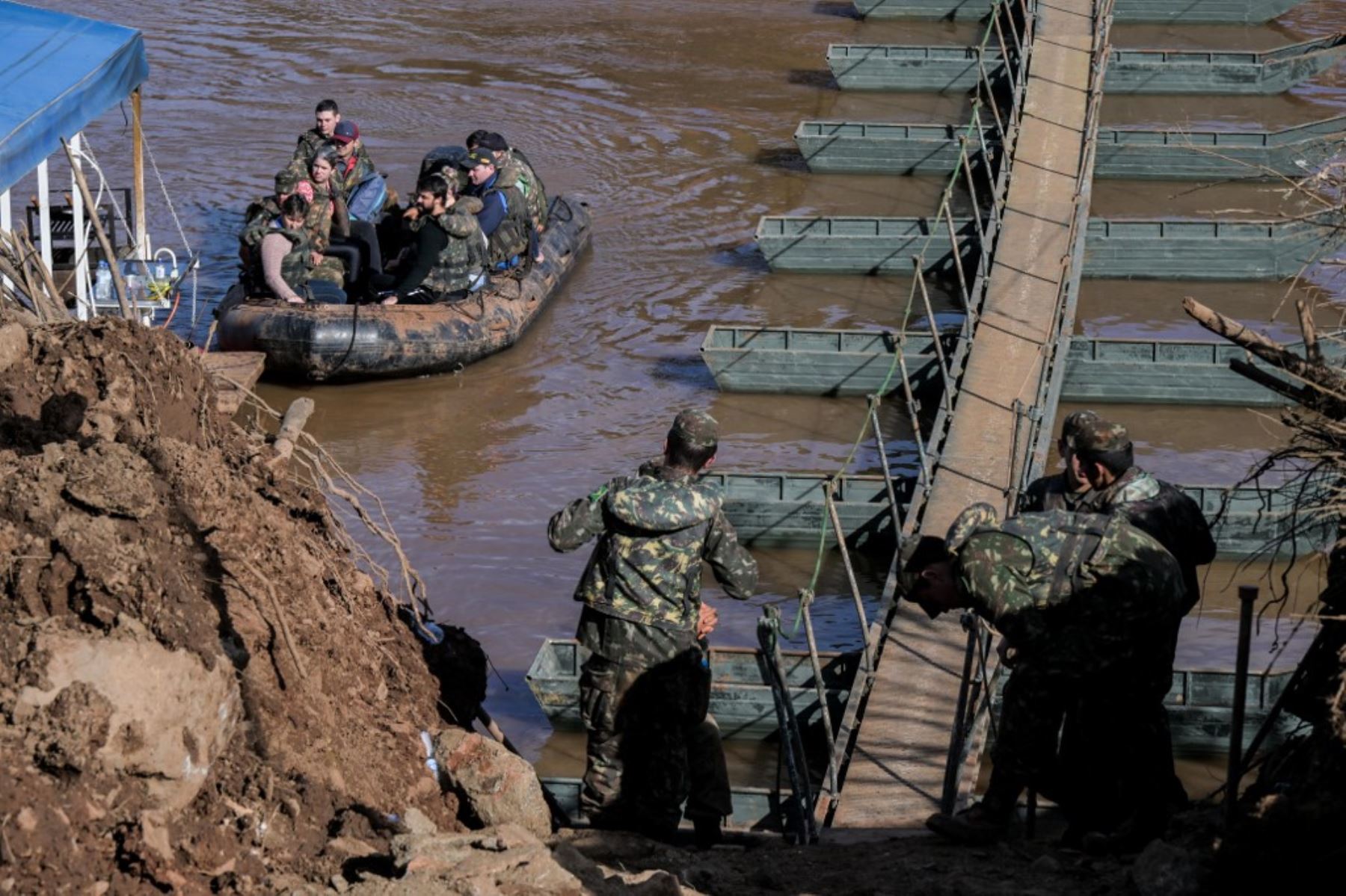 Personal militar ayuda a personas a cruzar un barco desde Arroio do Meio hacia Lajeado, sobre el río Forquilha, ya que el puente sobre el río en la Rodovia RS130 cayó durante las recientes inundaciones, en el estado de Rio Grande do Sul. Foto: AFP