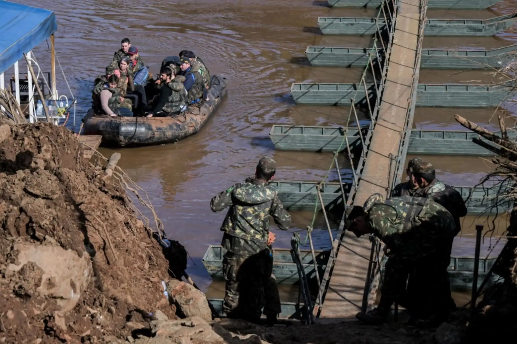 Personal militar ayuda a personas a cruzar un barco desde Arroio do Meio hacia Lajeado, sobre el río Forquilha, ya que el puente sobre el río en la Rodovia RS130 cayó durante las recientes inundaciones, en el estado de Rio Grande do Sul. Foto: AFP